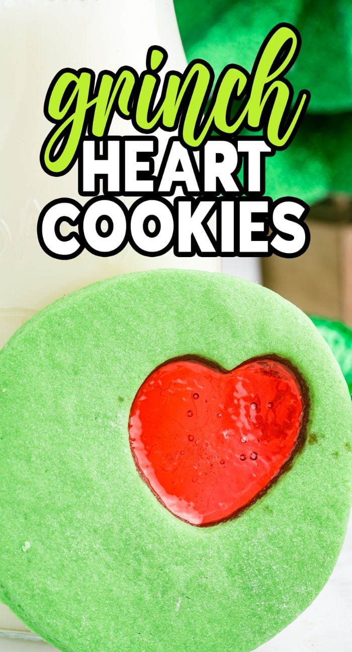 A green cookie with a red heart center, labeled "Grinch Heart Cookies" in bold text above—perfect festive treats for anyone who loves Grinch cookies or classic red and green Christmas cookies.