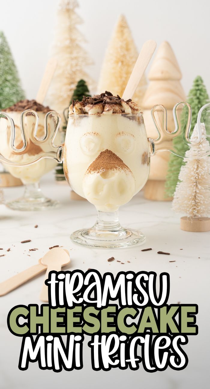 A reindeer-themed tiramisu trifle cheesecake in a glass, crafted with soft ladyfingers and mascarpone, set against mini Christmas trees for a festive touch.