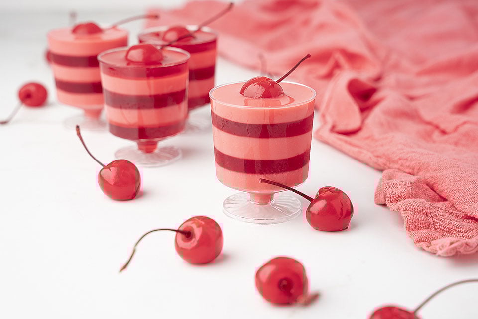 A group of red and white striped cups with cherries in them.