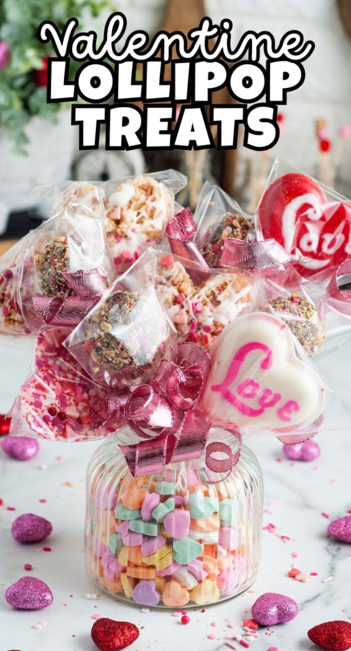 Glass jar filled with candy hearts, holding Valentine Lollipop Treats and lollipops wrapped in clear bags with pink bows—a perfect Valentine’s Day treat.