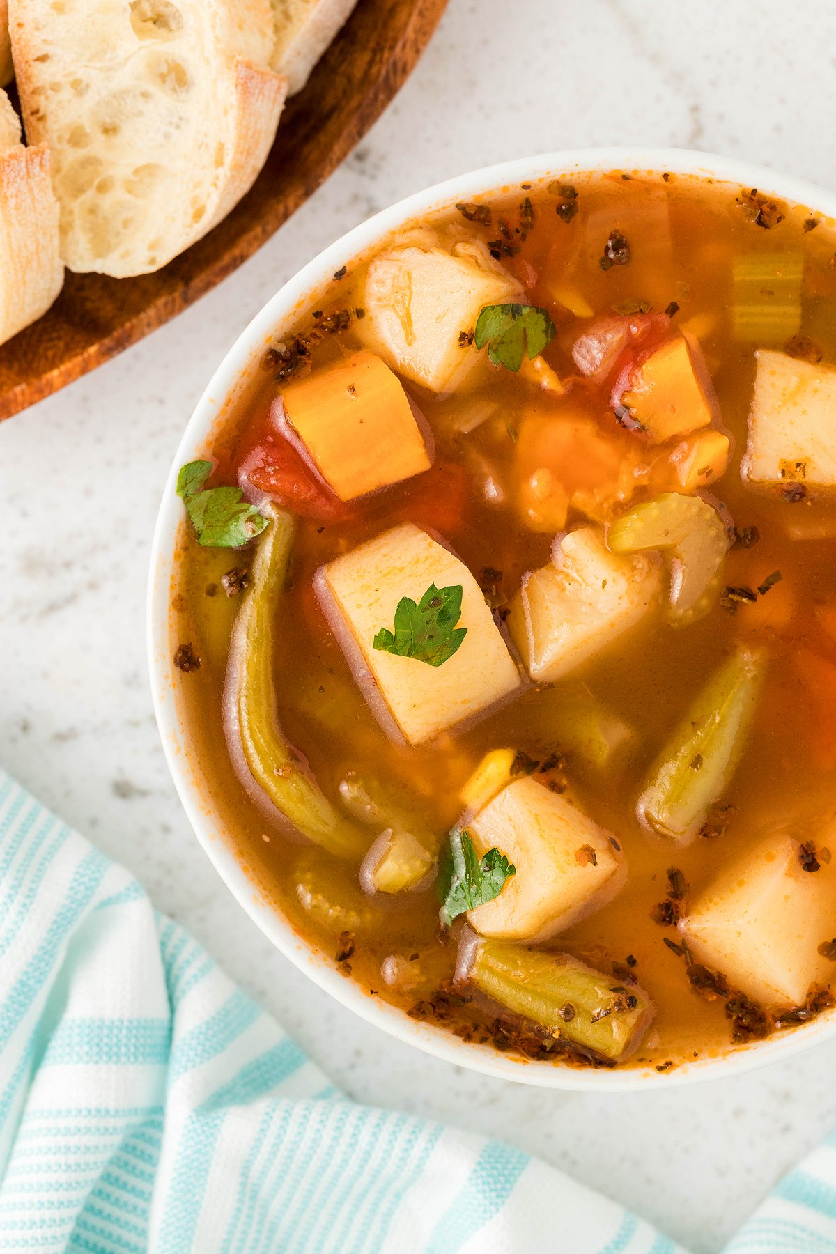A bowl of Instant Pot Vegetable Soup with bread on the side, photographed from above on a white surface—an easy and delicious 30 Minute Meal.