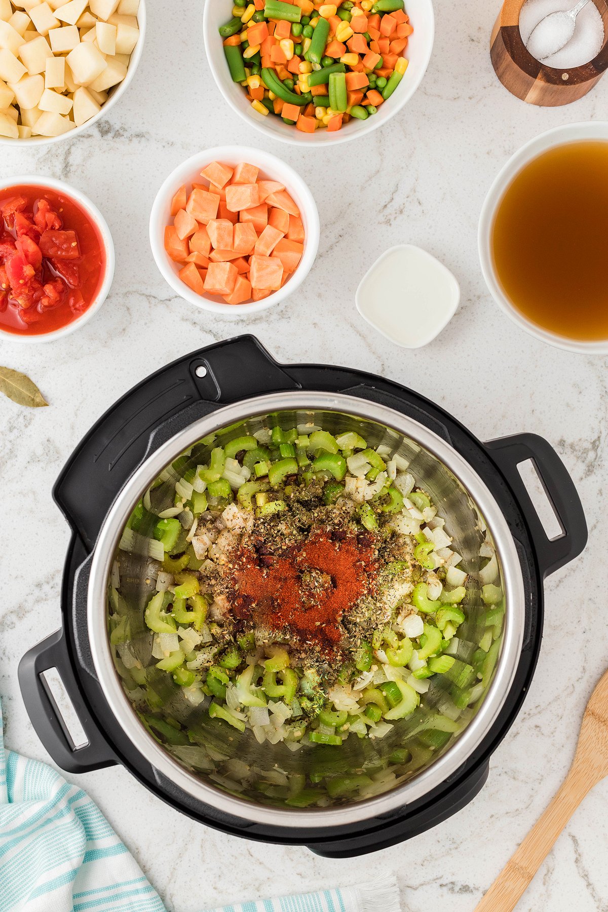 Top view of an Instant Pot with chopped celery, onion, and spices, surrounded by bowls of diced veggies—perfect for making soup in an Instant Pot or pressure cooker as a quick 30 Minute Meal.