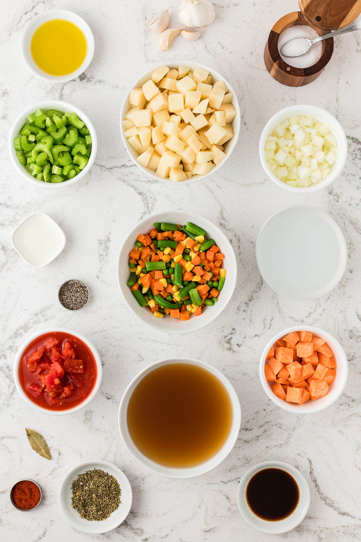 Ingredients for Instant Pot Vegetable Soup arranged in bowls on a white countertop, including fresh and frozen vegetables, broth, and seasonings—perfect for making soup in an Instant Pot or pressure cooker.
