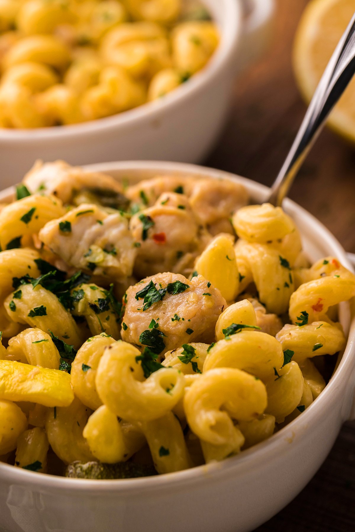 Creamy Instant Pot Lemon Chicken Pasta with tender chicken pieces, garnished with chopped parsley, served in a white bowl.