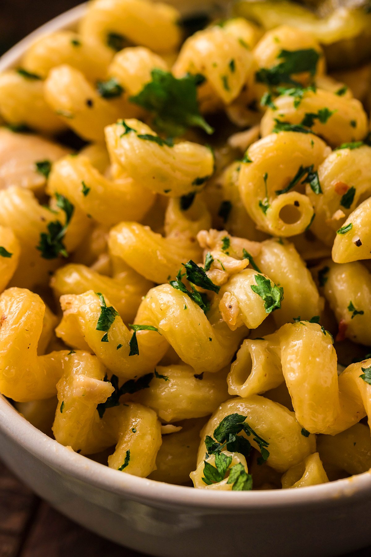 Close-up of creamy instant pot pasta dinner garnished with chopped parsley in a white bowl.