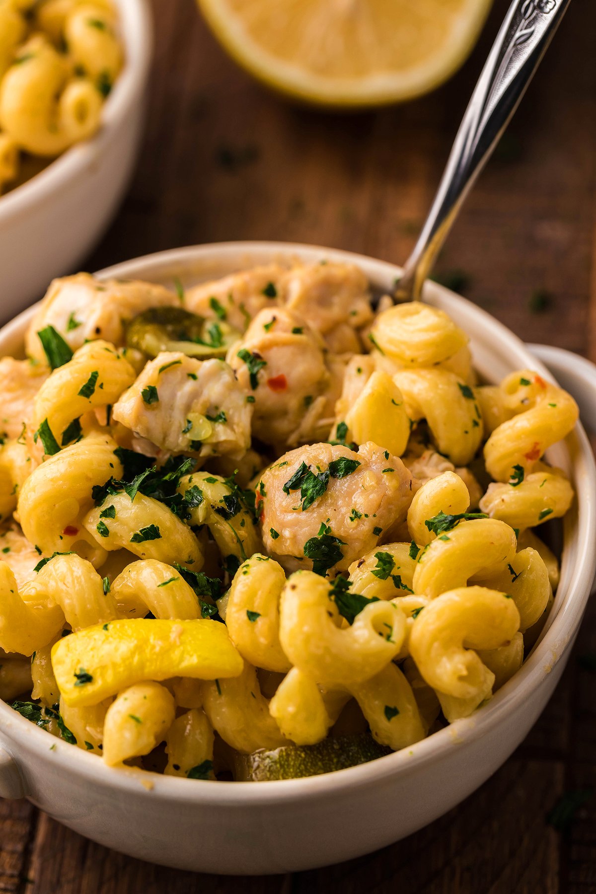 A bowl of curly pasta with chicken, yellow bell peppers, and fresh herbs, featuring a fork inside—perfect for an easy instant pot pasta dinner or when you crave pasta with chicken and vegetables.