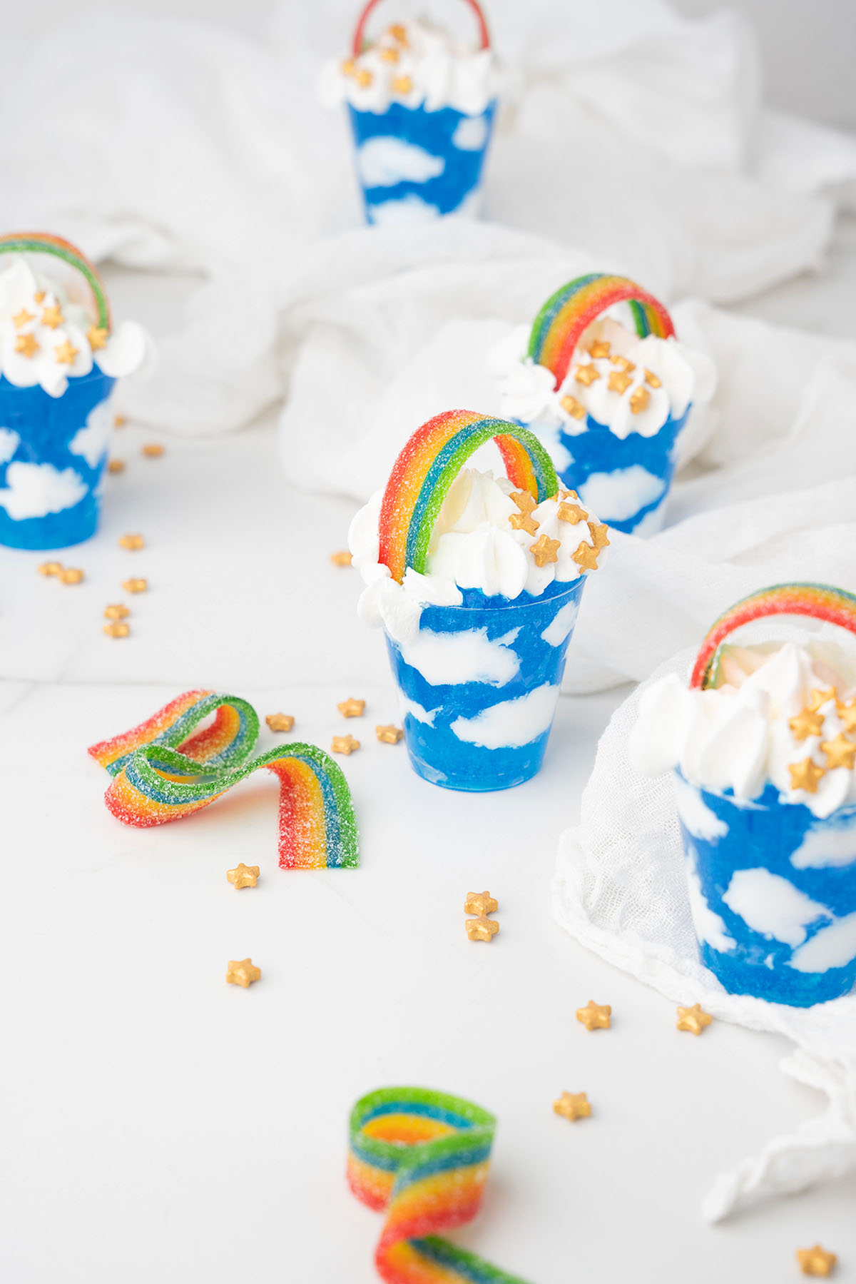 Blue dessert cups with Jello sky and cool whip clouds, topped with rainbow candy and star sprinkles, make these treats perfect for a festive St. Patrick&rsquo;s Day cocktail table.