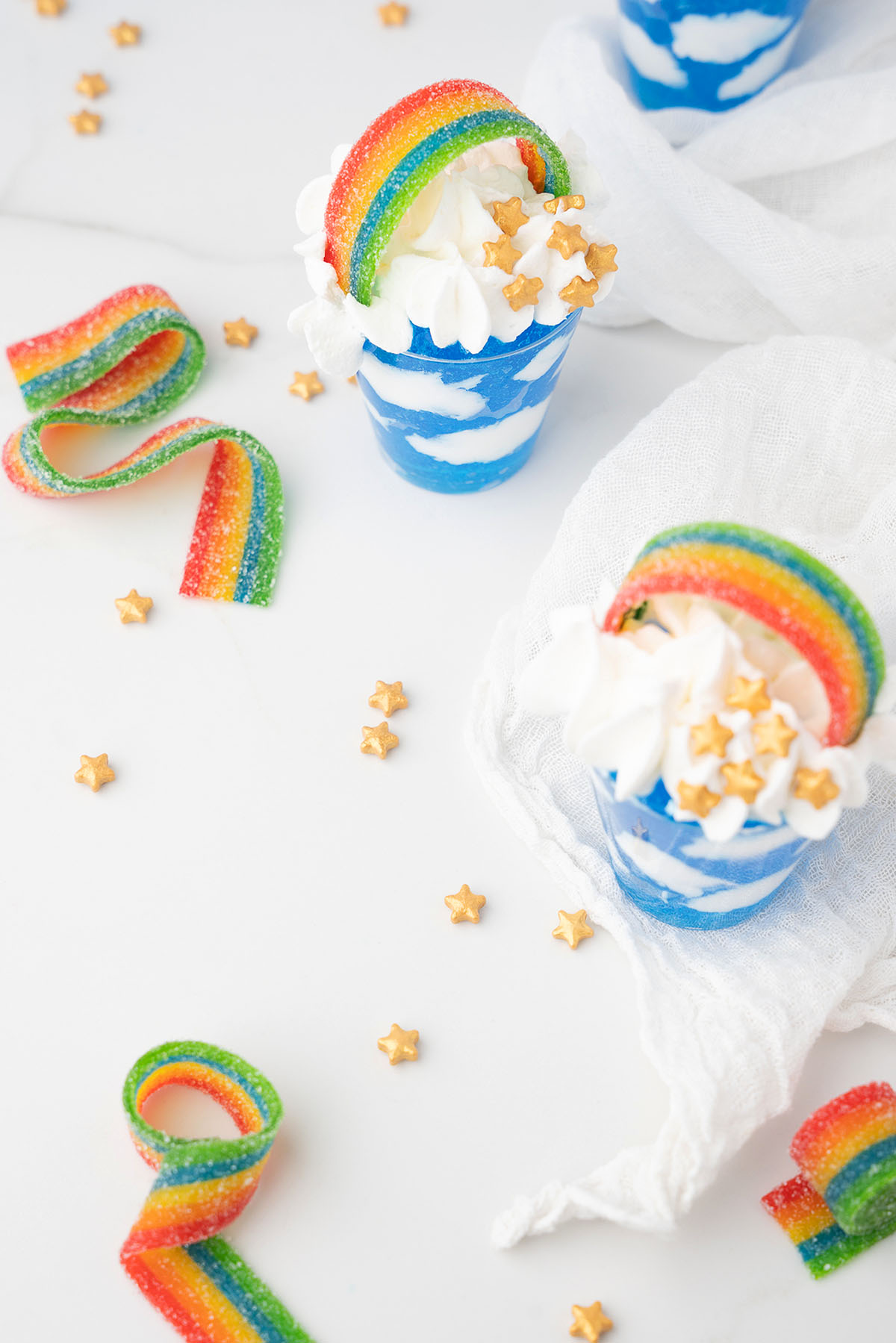 Blue and white parfaits topped with whipped cream, candy rainbow strips, and gold star sprinkles make a festive treat for Pride Day or as colorful Rainbow shots for your next celebration.