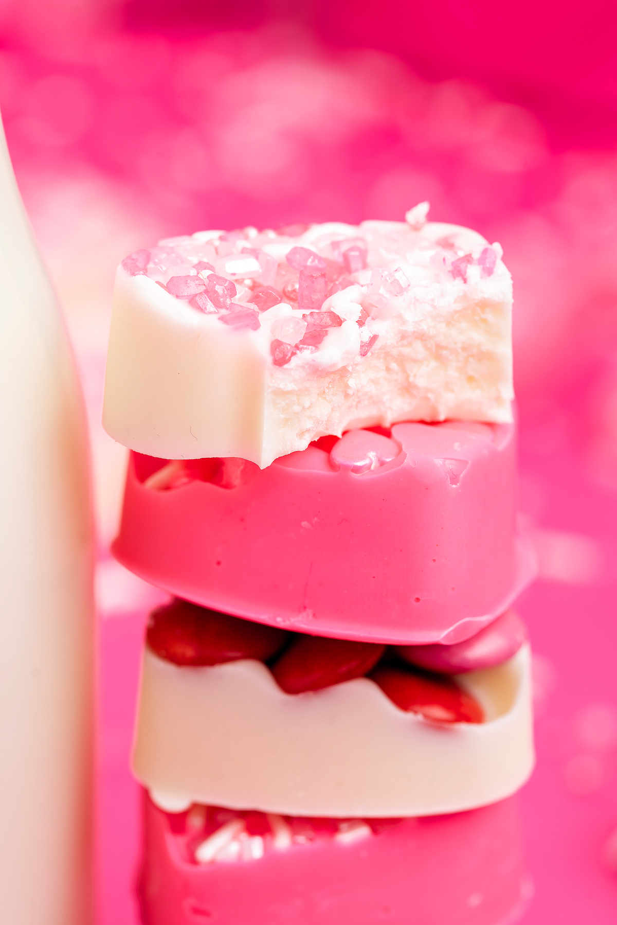 Three stacked pink and white heart-shaped soaps with candy and sugar toppings, against a pink background—perfect inspiration for easy Valentine’s treats or heart shaped chocolate treats.