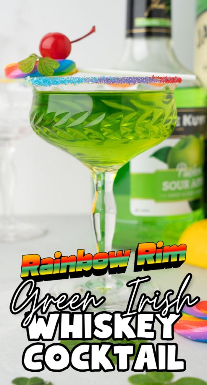 A green cocktail featuring sour apple schnapps and melon liqueur in a glass with a rainbow sugar rim, cherry, and rainbow candy garnish. Text: Rainbow Rim Green Irish Whiskey Cocktail—perfect for St. Patrick’s Day or Pride Day.