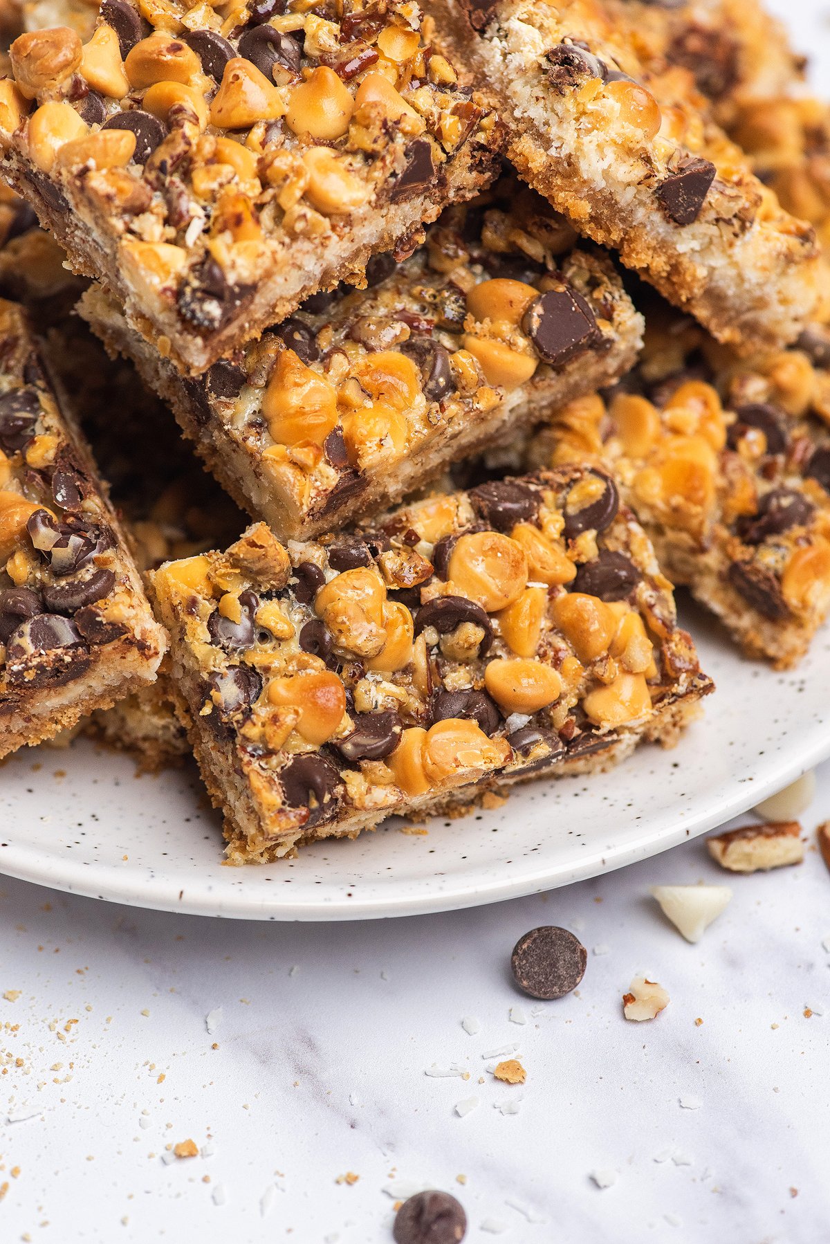 A plate of Hello Dolly bars topped with butterscotch and chocolate chips, stacked and ready to serve.
