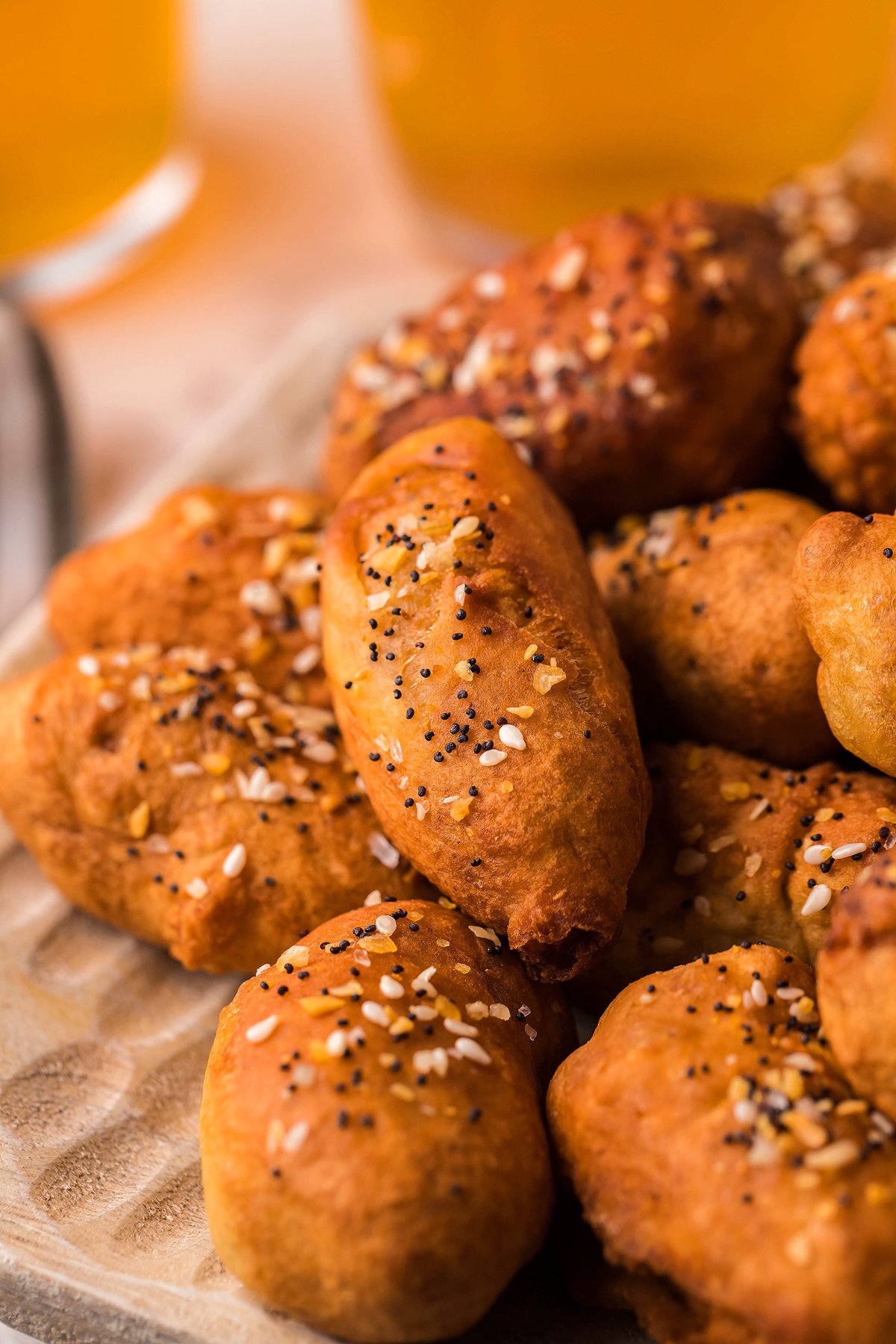 Golden brown, seeded bread rolls on a plate make the perfect appetizer or finger food, with drinks in the background.