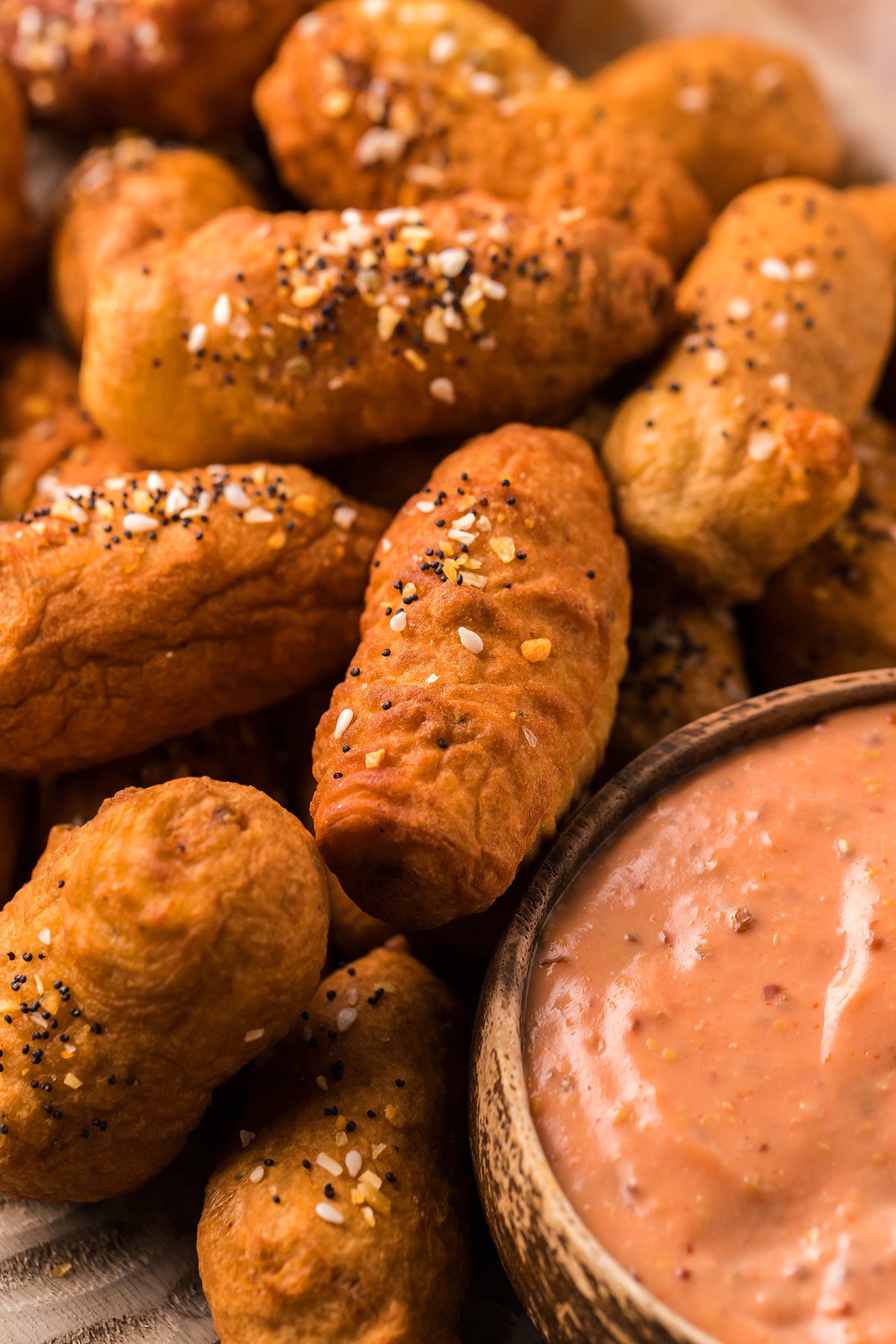 Golden brown pretzel bites topped with seasoning, next to a bowl of creamy pink dipping sauce—perfect as a game day appy or delicious appetizer or finger food for any gathering.