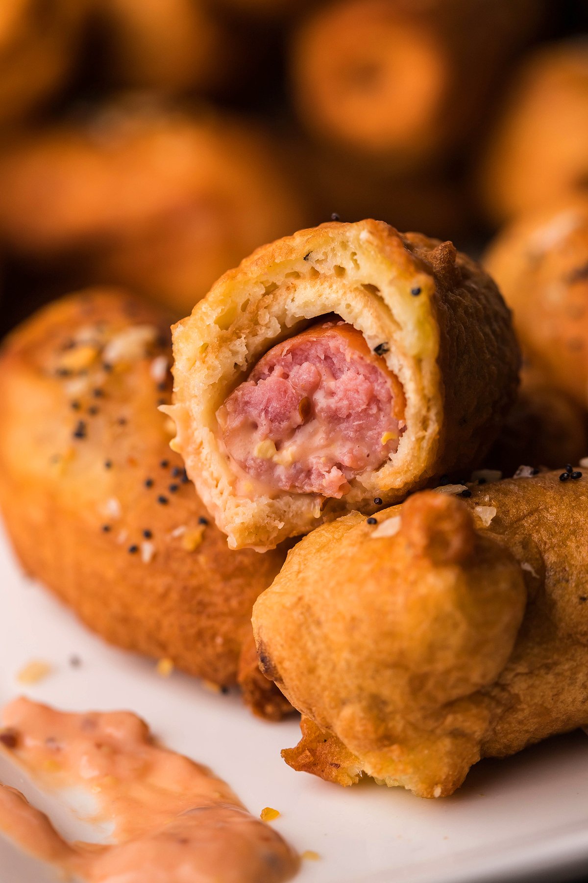 A close-up of a flaky pastry filled with beer battered little smokies, with one piece bitten to show the filling—perfect as a game day appy alongside Easy horseradish Mayo Dipping Sauce.