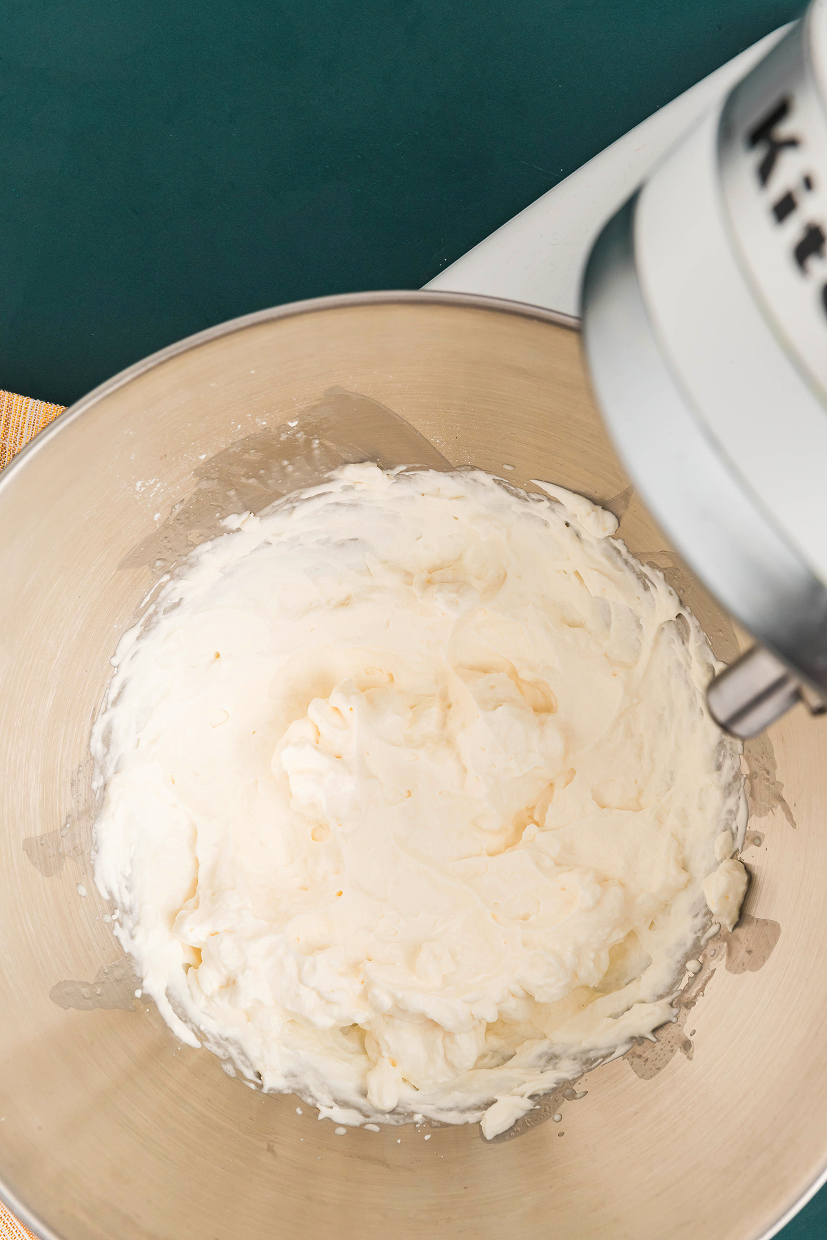 Whipped cream in a stainless steel mixing bowl attached to a stand mixer, viewed from above—perfect for topping your Irish cream milkshake or adding the finishing touch to a boozy shamrock shake.