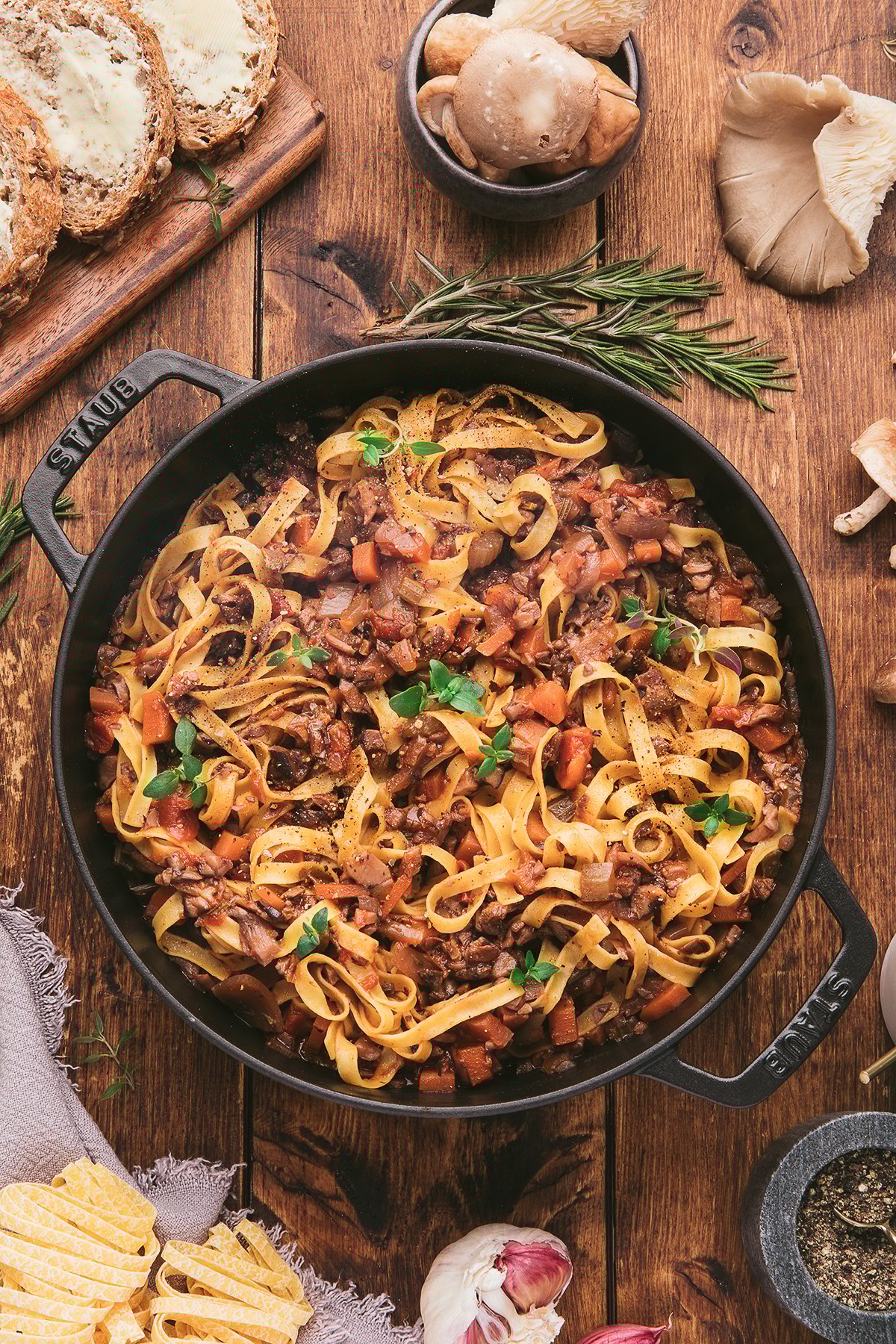 Tagliatelle pasta with a savory meatless ragu—a homemade spaghetti sauce with mushrooms and vegetables—served in a black pan on a rustic wooden table.