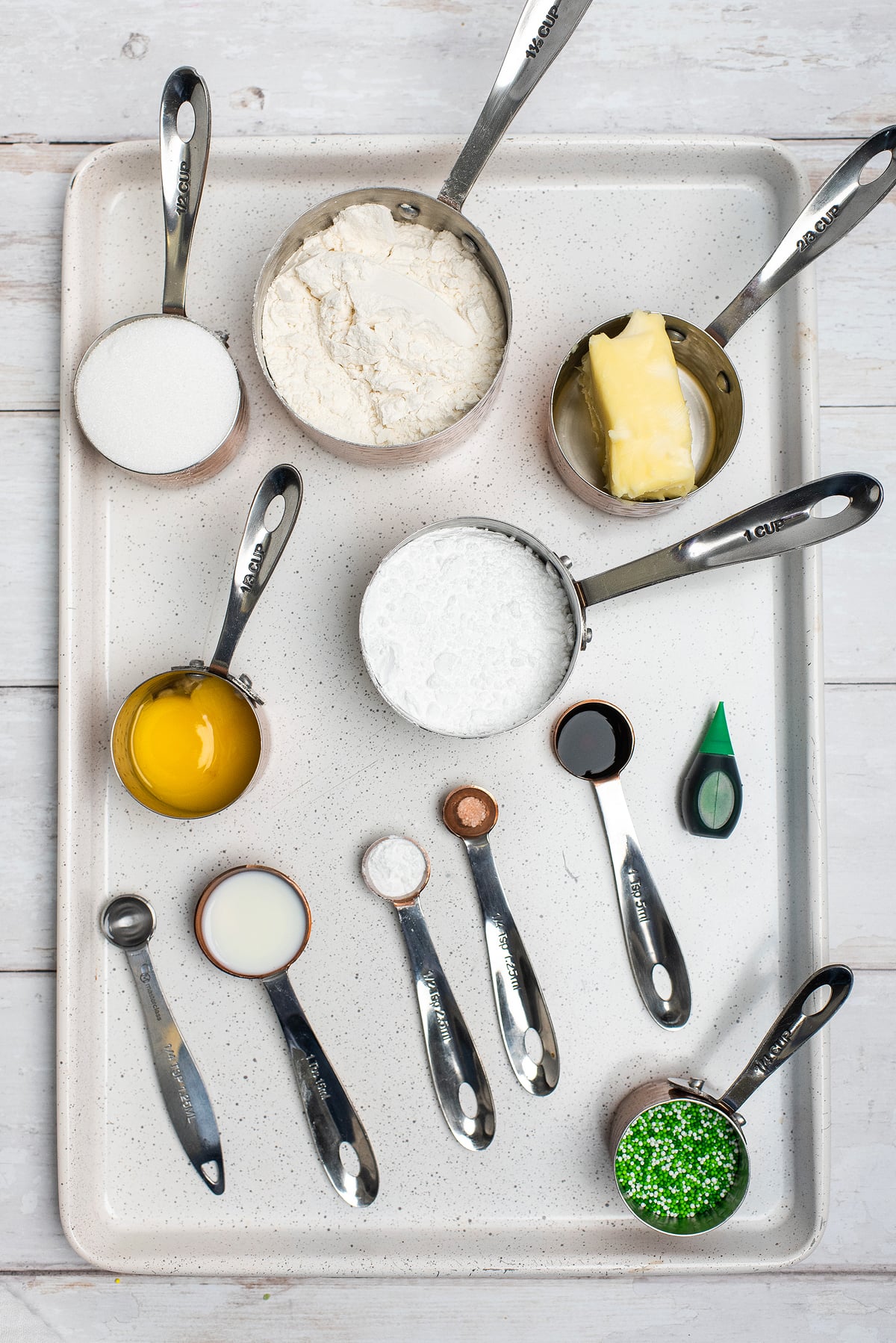 Baking ingredients in measuring cups and spoons on a tray, ready for making shamrock sugar cookies or trying a fun St. Patrick’s Day cookie recipe with sprinkles. Perfect for festive treats inspired by classic Dunkaroos!.
