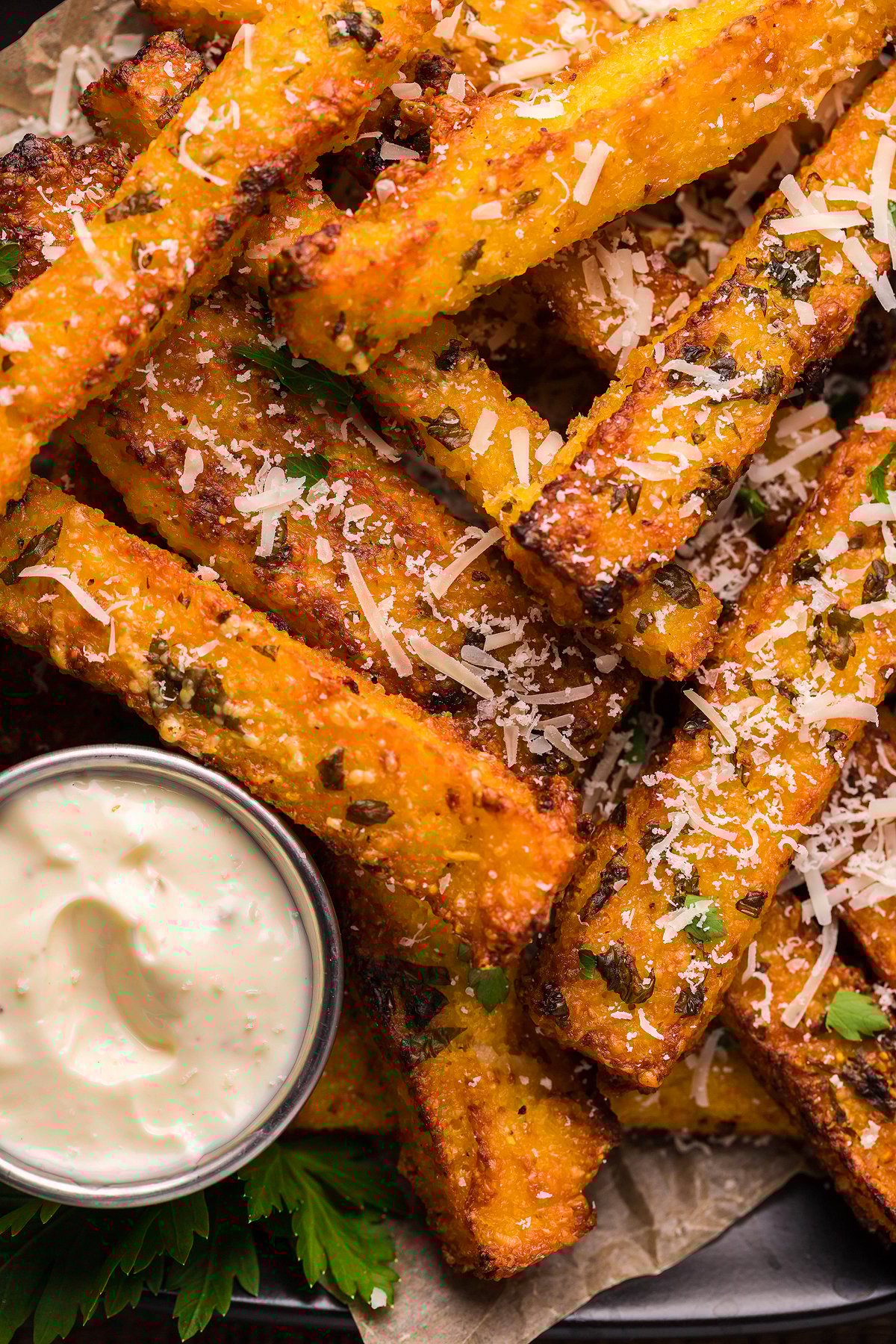 Golden cornmeal French fries topped with shredded cheese and herbs, served as a side dish or appetizer with a creamy truffle mayo dipping sauce.