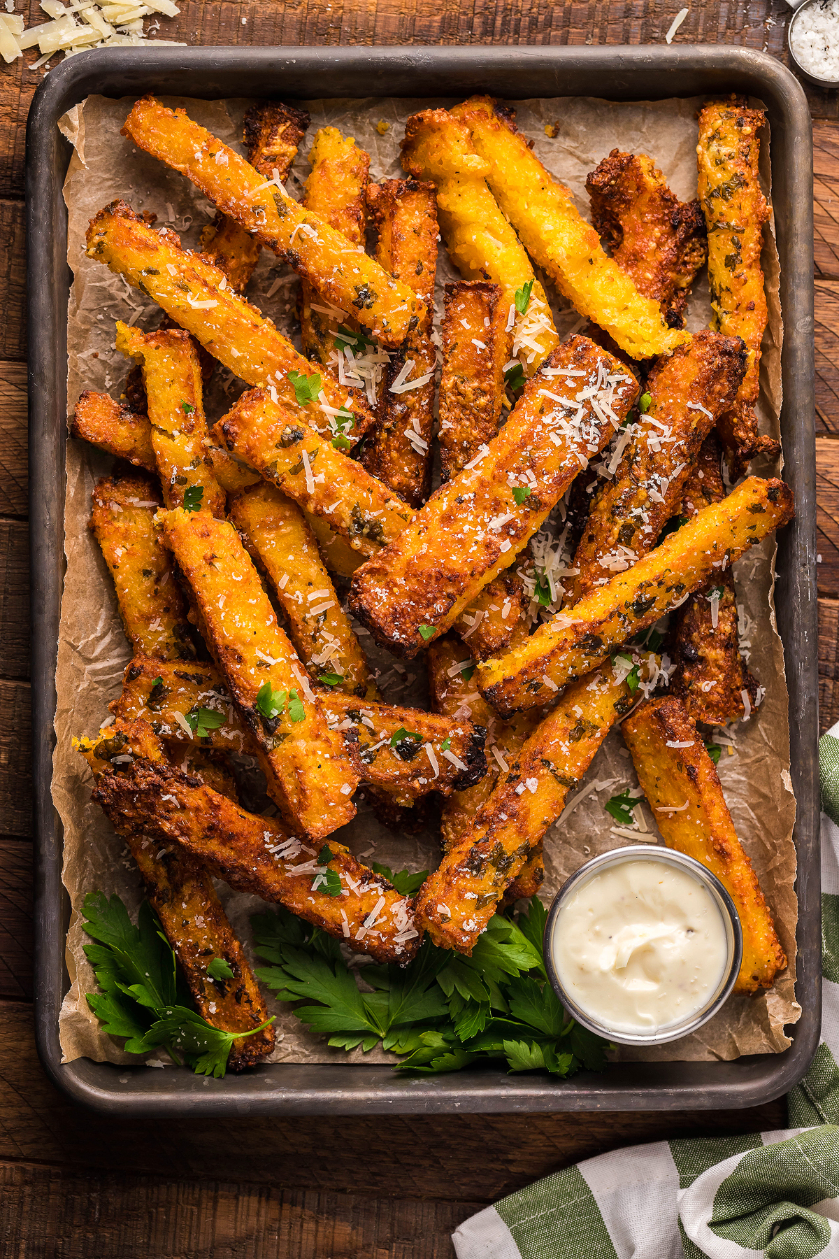 Crispy Air Fryer Polenta Fries made from cornmeal french fries, topped with grated cheese and herbs, served with a side of dipping sauce—perfect as a side dish or appetizer.