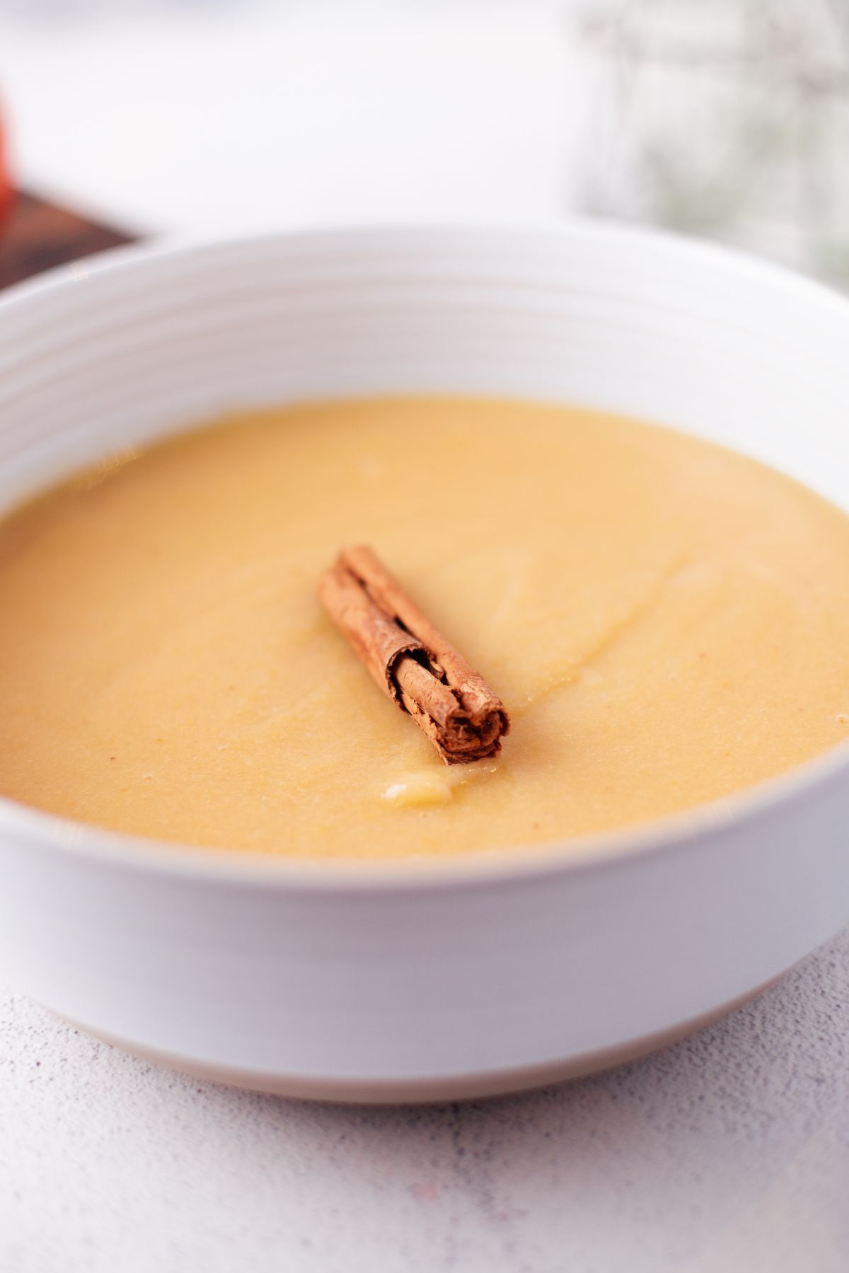 A bowl of creamy soup with a cinnamon stick garnish in the center, inspired by comforting applesauce variations.