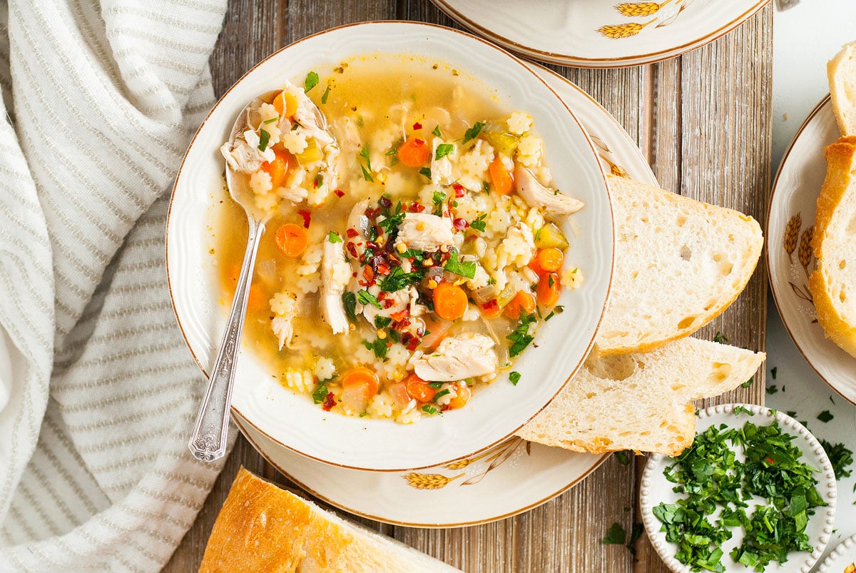 Chicken pastina soup wtih tiny star pasta shapes in a bowl.