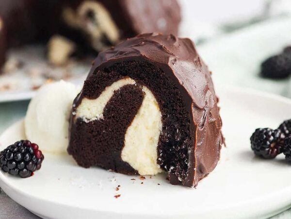 A slice of Chocolate Bundt Cake with a luscious cream cheese swirl, served with blackberries and a scoop of ice cream.
