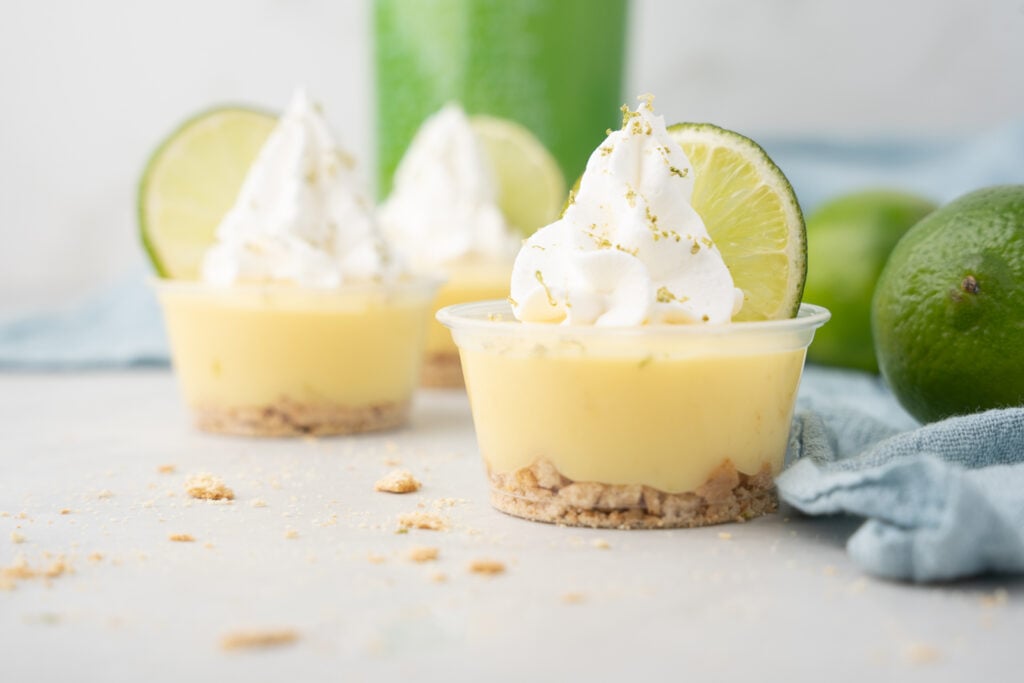 Mini lime cheesecakes with whipped cream and limes.