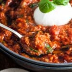 Bowl of Italian Tomato and Bread Soup, or Pappa al Pomodoro, featuring tomato-based sauce with mozzarella and basil on top, spoon resting inside; perfect for using stale or leftover bread and tomatoes.