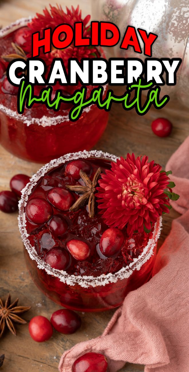 Two Holiday Cranberry Margaritas with sugared rims, silver tequila and triple sec, garnished with cranberries and red flowers, on a rustic table—perfect as a Thanksgiving or Christmas cocktail.