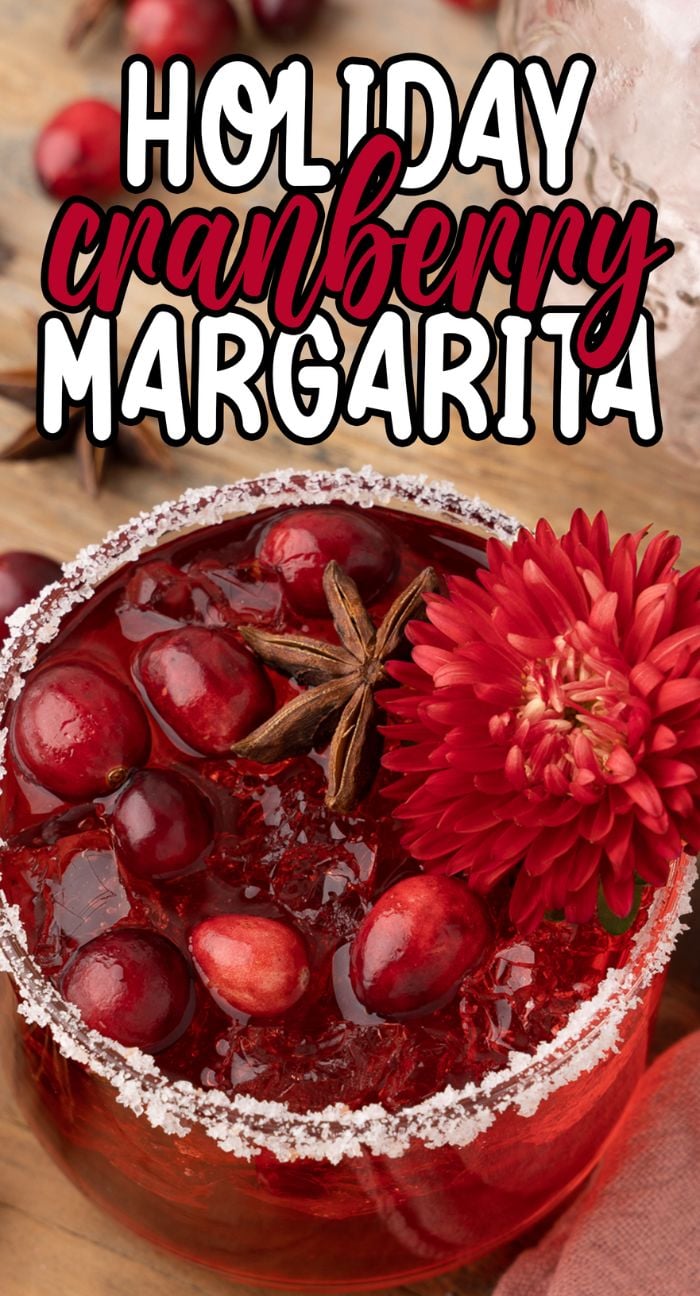 A festive cranberry drink, this Holiday Cranberry Margarita is garnished with cranberries, star anise, and a red flower, served with a salted rim.