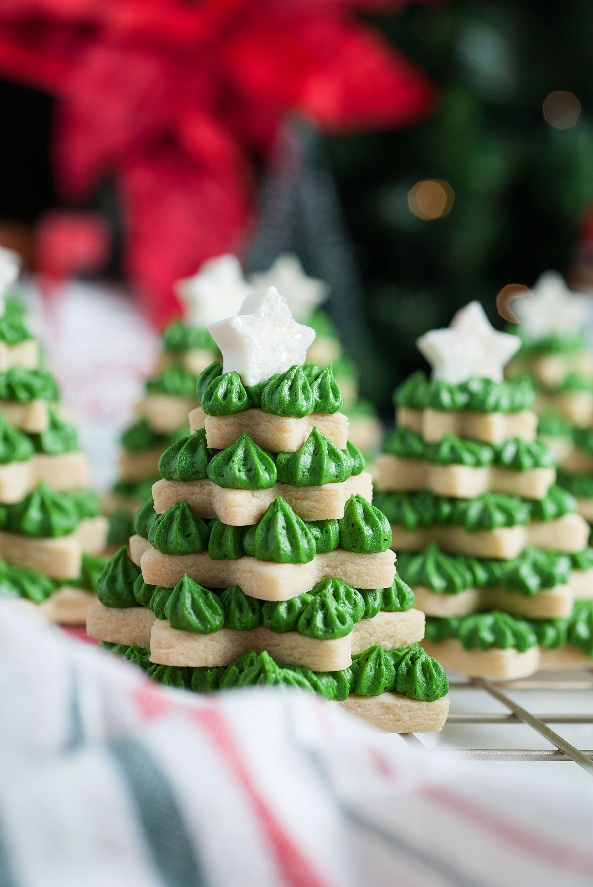 Stacked 3D Christmas Tree Sugar Cookies with green frosting and a white star on top, set on a cooling rack. Perfectly shaped using star cookie cutters for festive holiday treats.