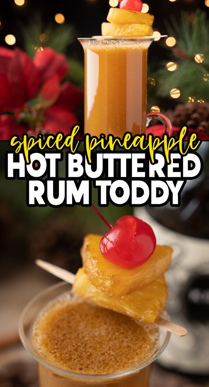 A Spiced Pineapple Hot Buttered Rum Toddy with pineapple and cherry garnish sits in front of festive holiday decor, offering a cozy blend of black spiced rum and butterscotch schnapps for your holiday celebration.