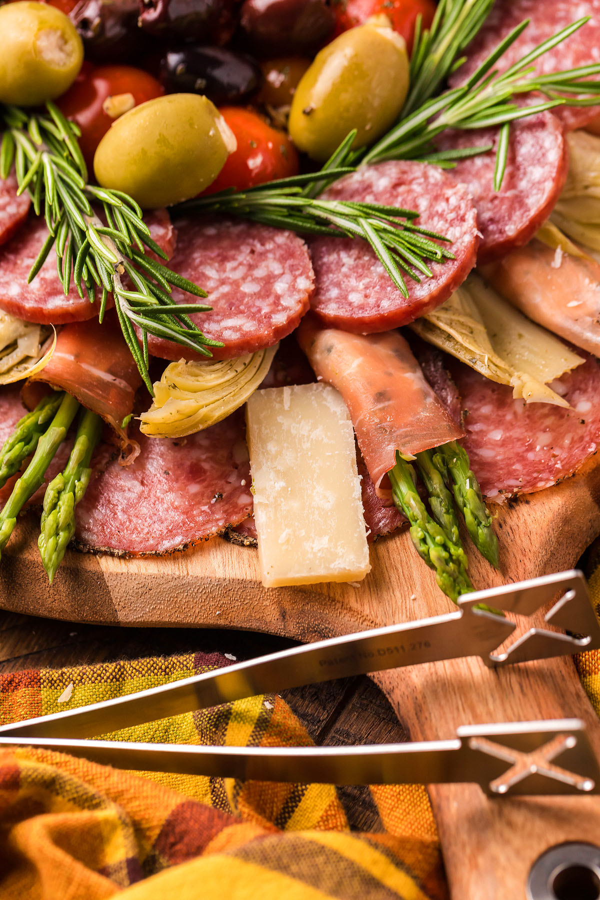 A classic Italian starter, this charcuterie board features salami, cheese, olives, artichokes, asparagus, and rosemary on a wooden platter—perfect for a festive Holiday Antipasto Wreath presentation.