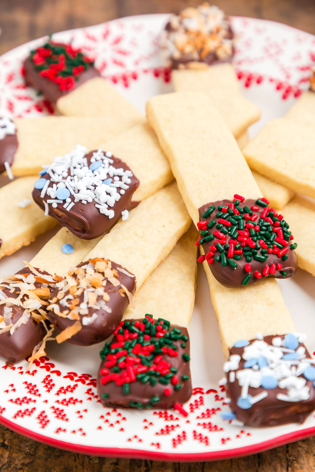Sprinkle decorated cookie sticks and chocolate dipped cookie sticks are arranged on a festive plate, perfect for your next cookie exchange.