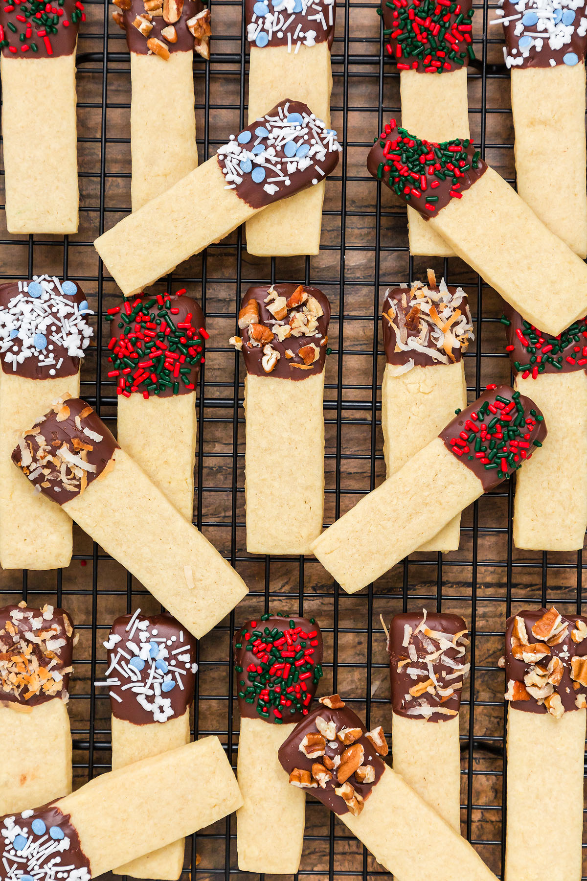 Rectangular Dipped Sugar Cookie Sticks dipped in chocolate and topped with sprinkles, coconut, or nuts&mdash;perfect for a Christmas cookie exchange&mdash;rest on a cooling rack.