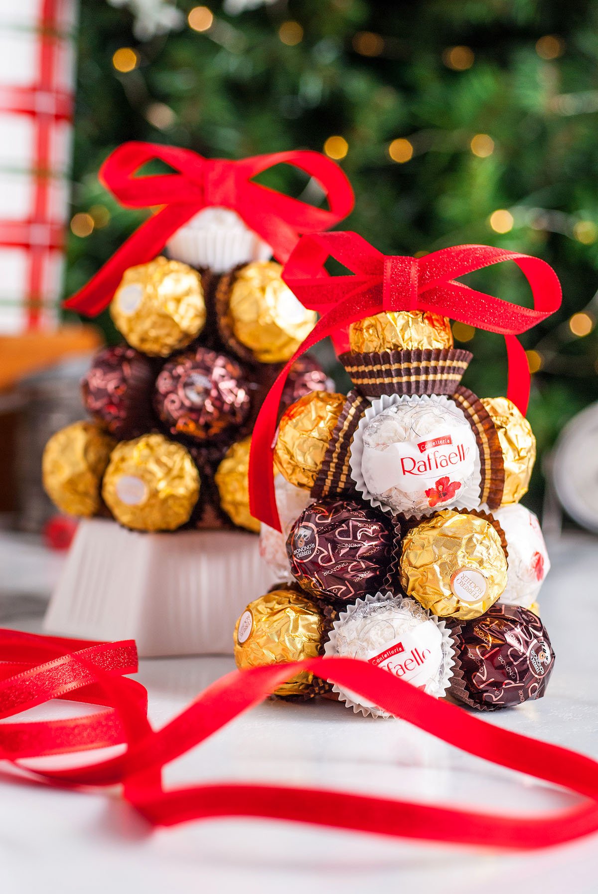 Chocolate and candy arranged in a tree shape, tied with a red ribbon, with a festive background—perfect as a Homemade Ferrero Rocher Christmas Tree or a sweet DIY Christmas decoration.