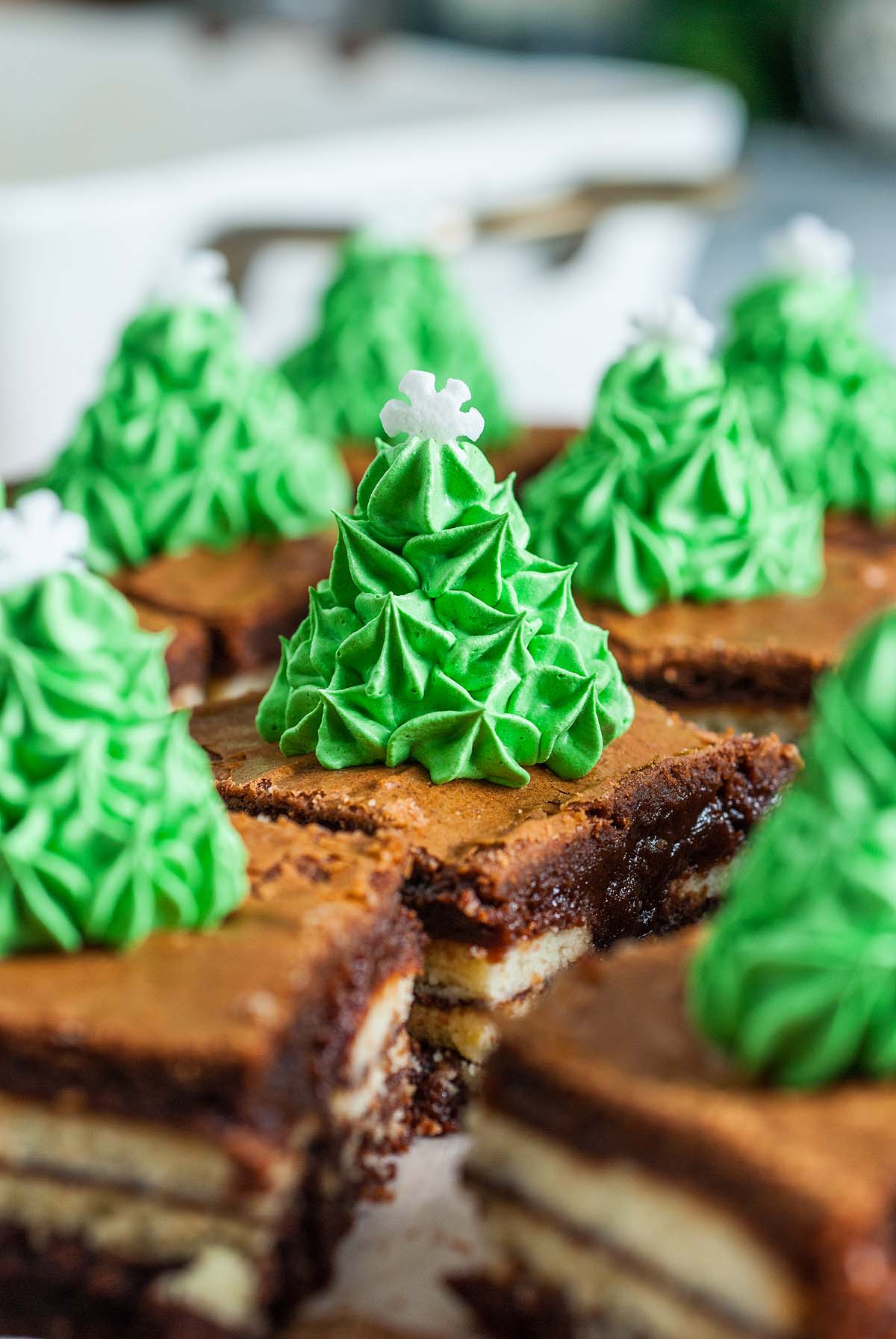 Brownie squares topped with green mint frosting, decorated with a Christmas tree design and a white snowflake—a delightful twist on classic Mint brownies.