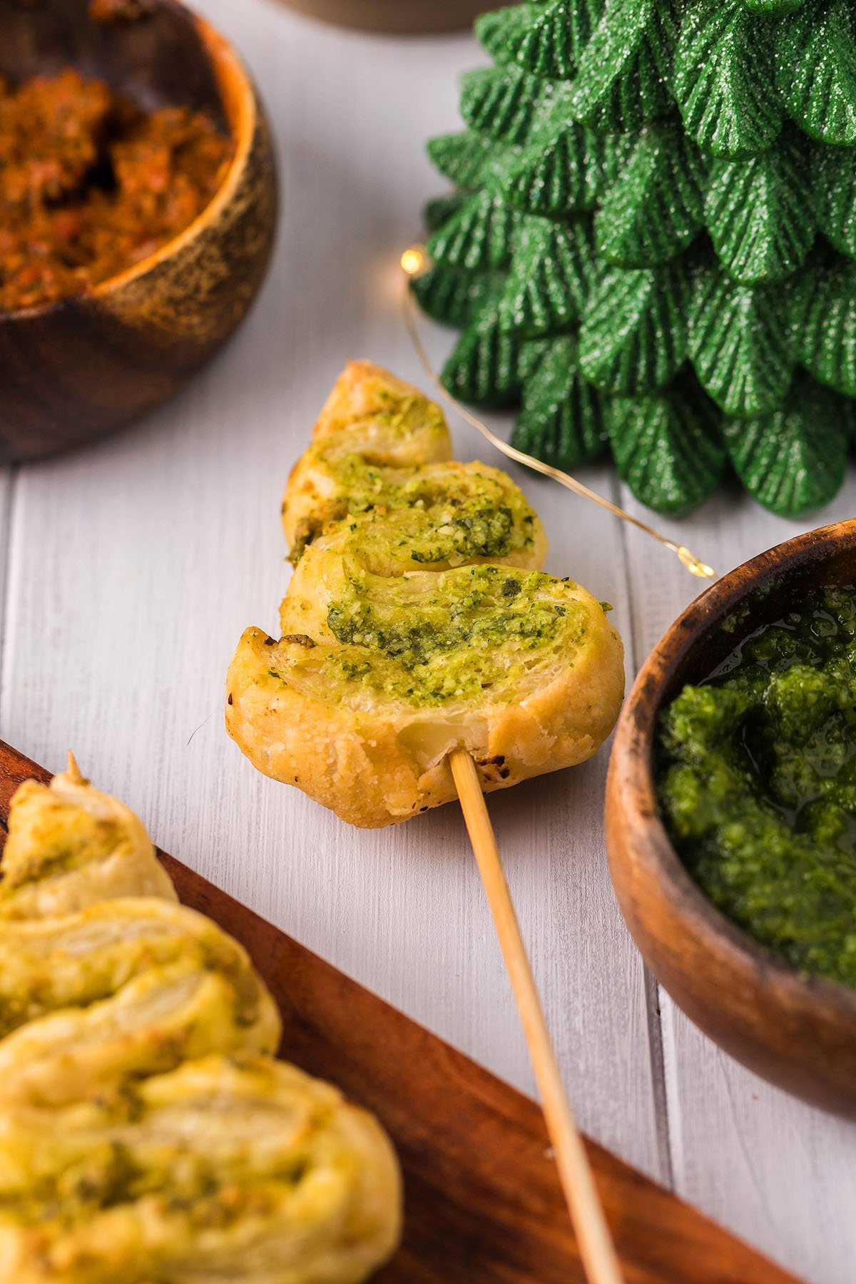 Pesto Puff Pastry Christmas Trees on skewers make charming christmas appetizers, surrounded by festive decorations and dips—a delightful puff pastry recipe for your holiday table.