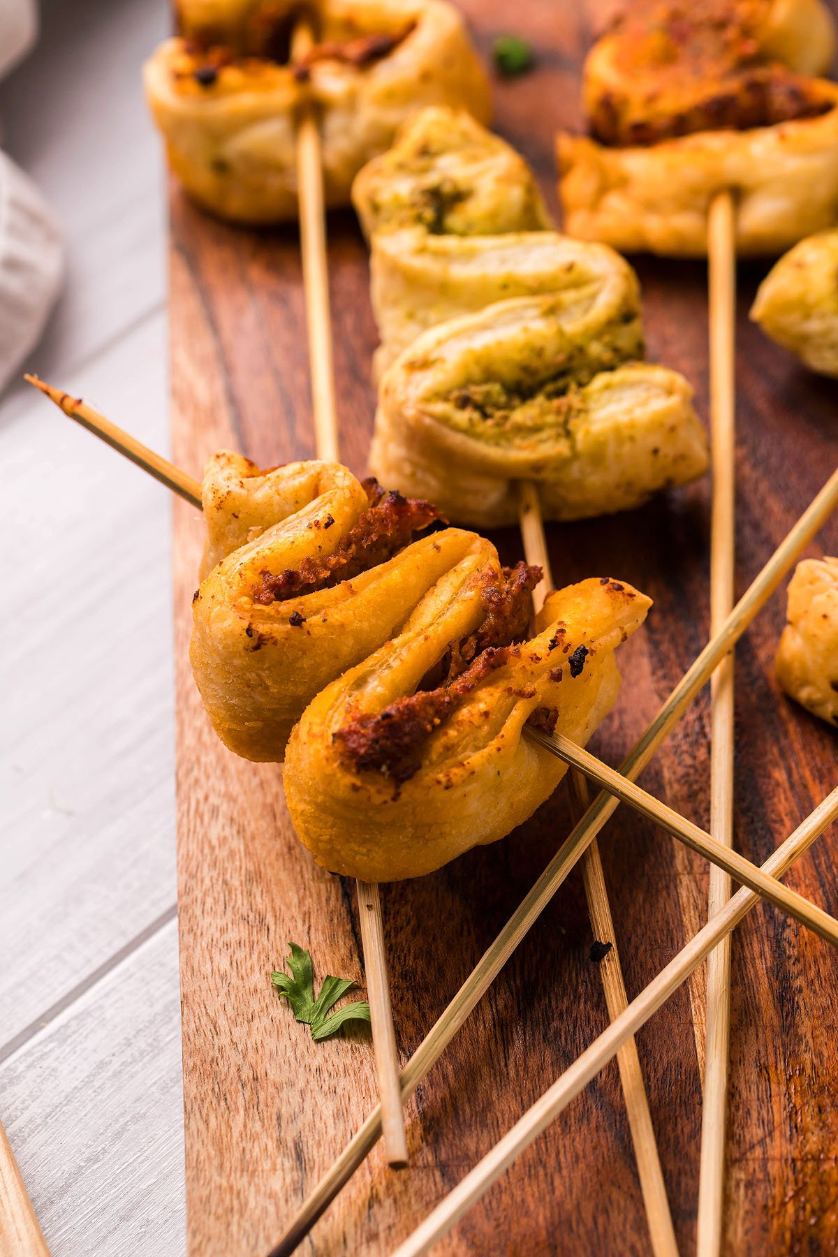 Close-up of Puff Pastry twists on wooden skewers, arranged on a wooden board—an easy Puff pastry recipe perfect for festive Christmas appetizers.