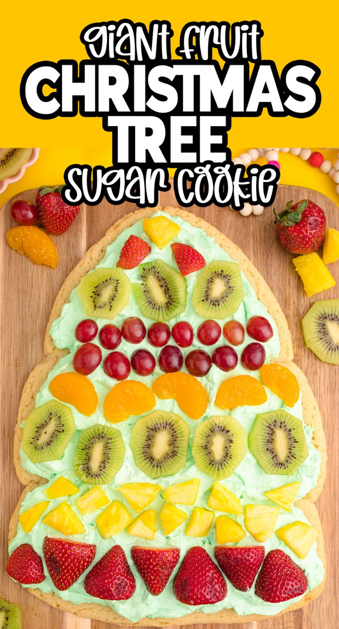 Giant Christmas Tree Fruit Sugar Cookie, a festive Christmas dessert, shaped like a tree and topped with green frosting and assorted fresh fruit slices.