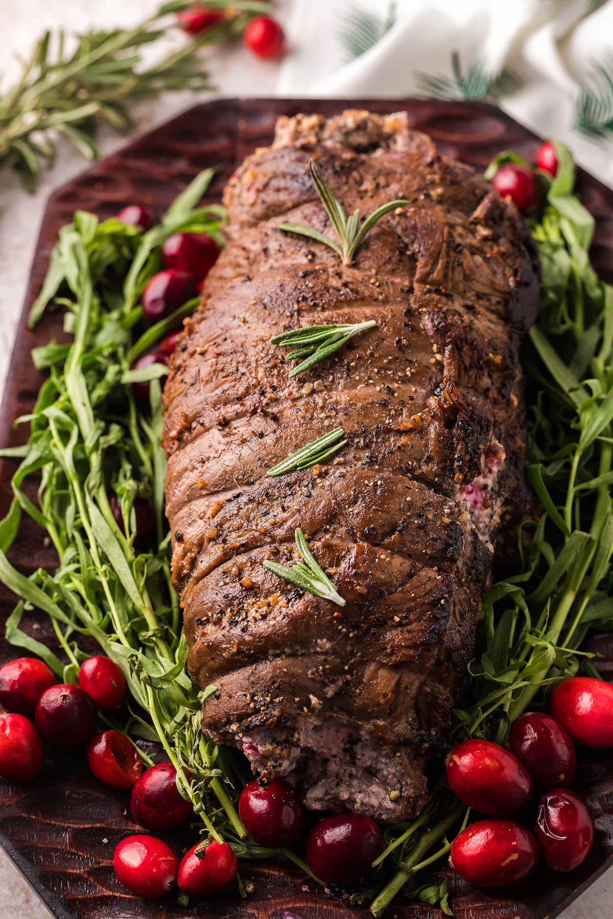Roast beef garnished with rosemary, surrounded by arugula and cranberries, makes an elegant Thanksgiving or Christmas steak recipe, perfect for festive gatherings.