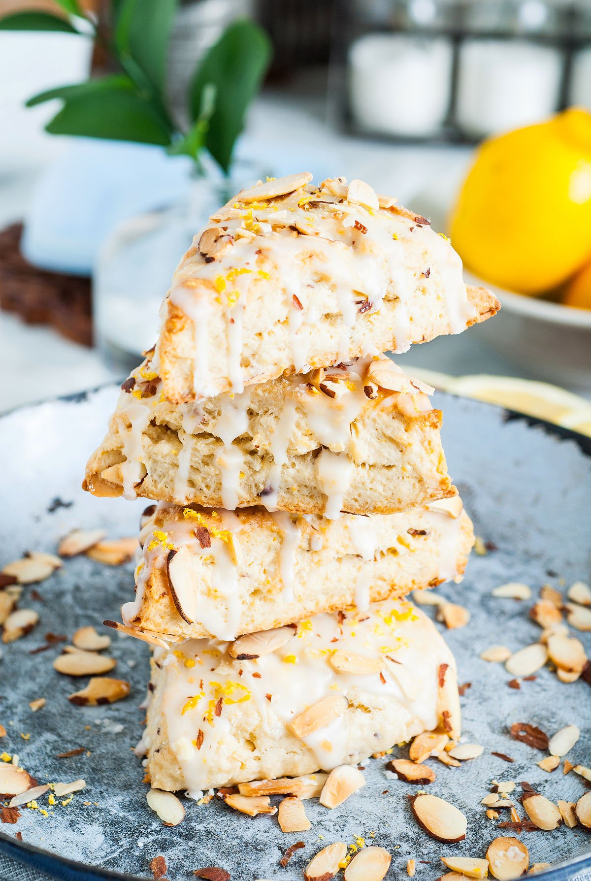 Three Lemon Almond Scones stacked on a plate, drizzled with icing and sprinkled with sliced almonds and lemon zest—an easy scone recipe perfect for any occasion.