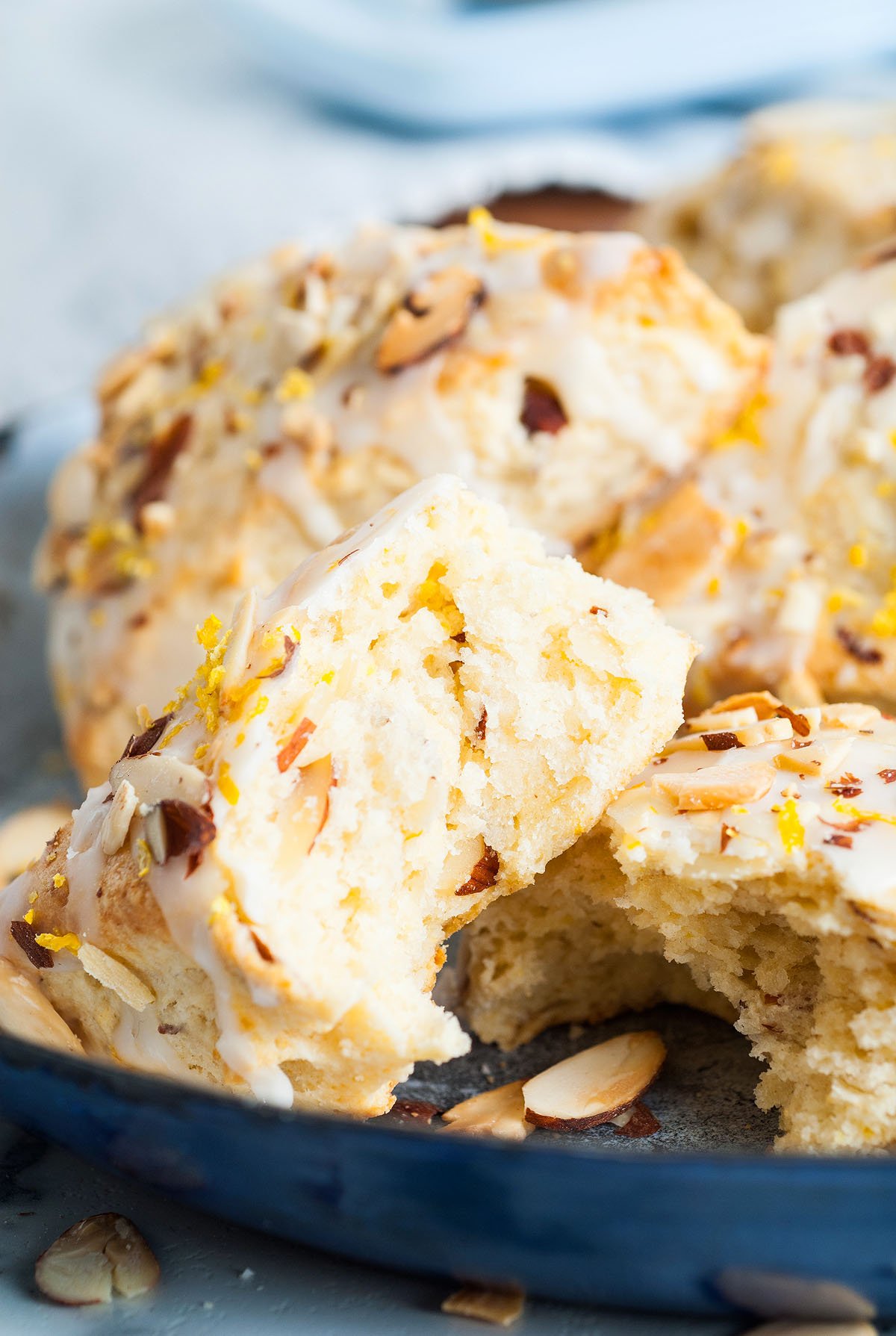 Flaky Lemon Almond Scones topped with icing and lemon zest, with one scone broken to show the tender inside—an easy scone recipe perfect for any occasion.