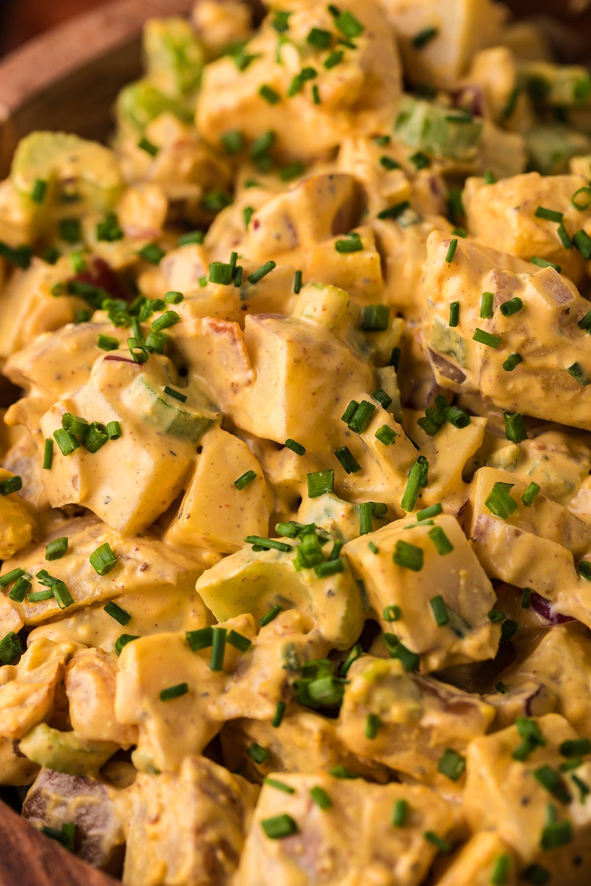 Close-up of creamy smoked potato salad, topped with chopped chives, celery, and bits of bacon—perfect for serving alongside your favorite Traeger grill or pellet smoker recipes.