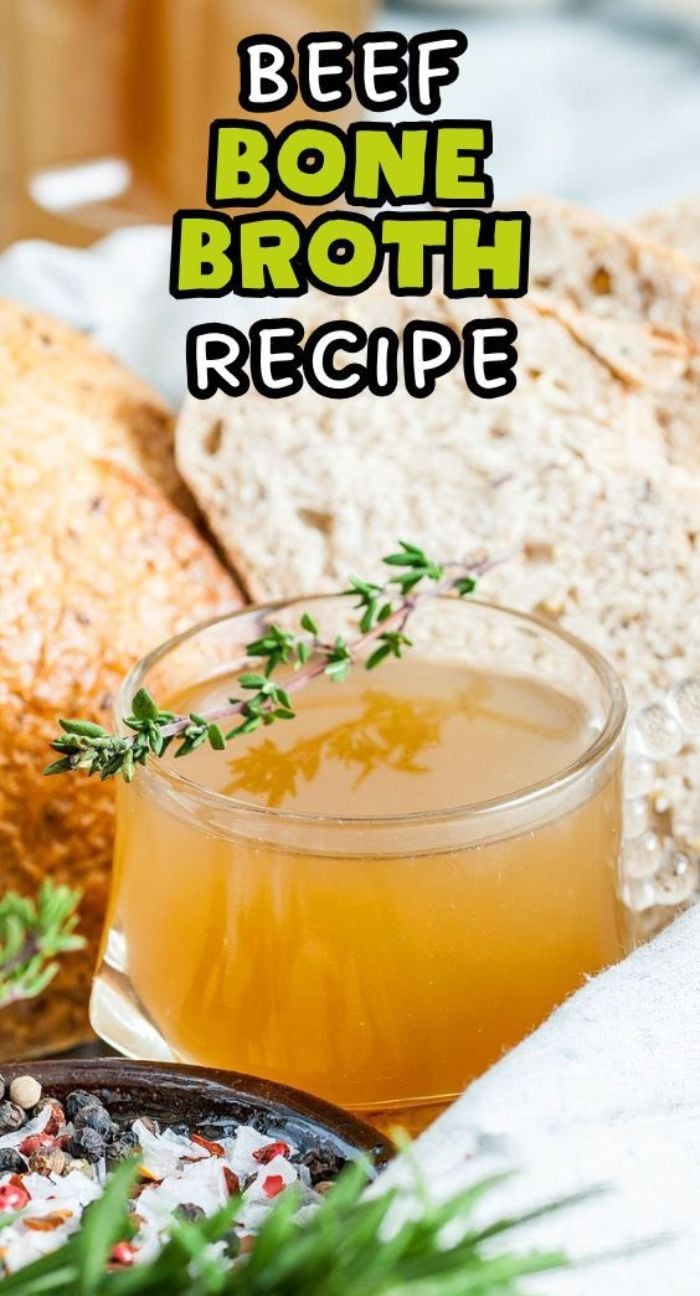 A glass cup of homemade bone broth garnished with thyme sits beside fresh bread. Text: Beef Bone Broth Recipe—learn how to make beef bone broth at home for rich, authentic flavor inspired by Brodo di Carne.