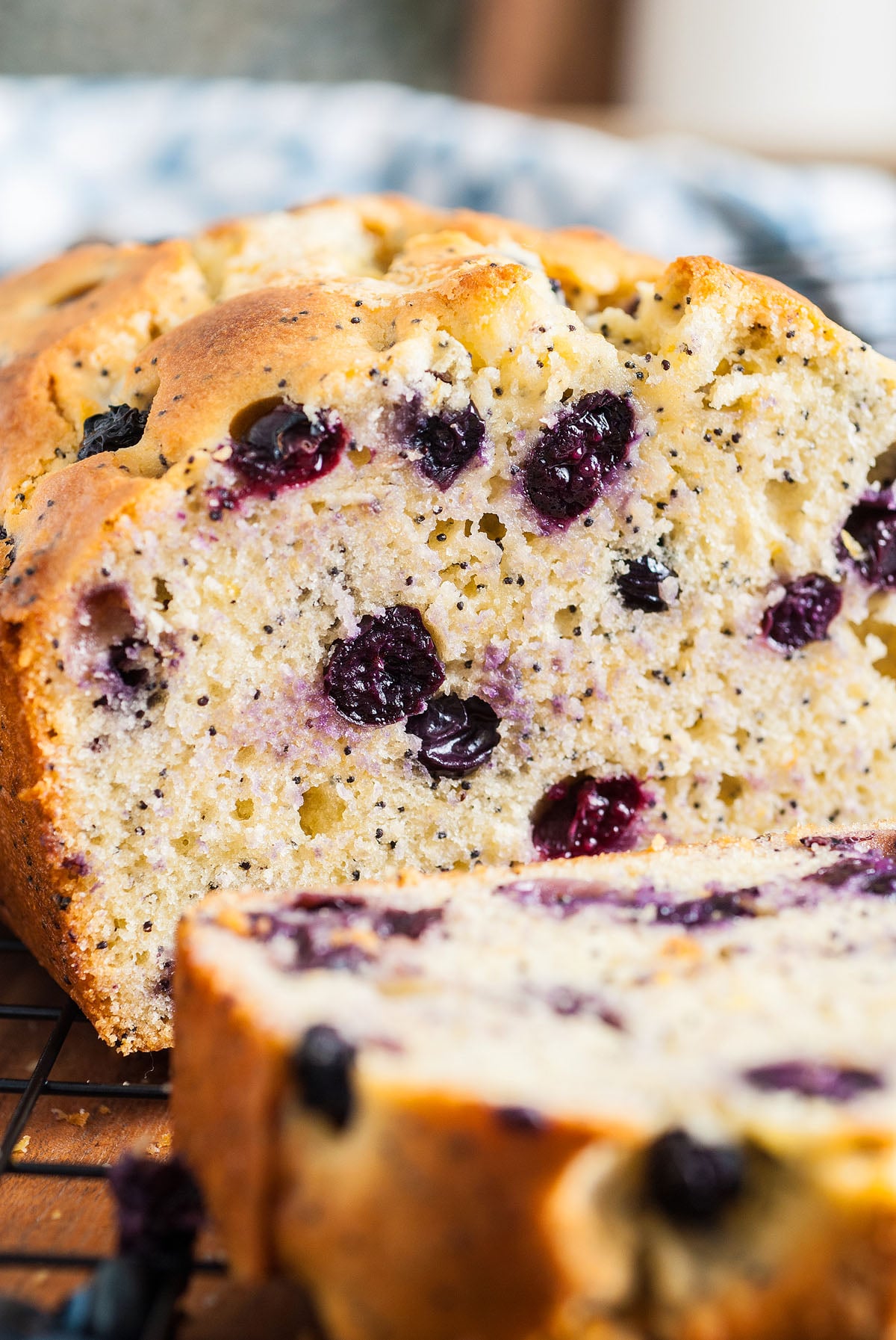 Close-up of sliced Lemon Blueberry Poppy Seed Loaf with juicy blueberries and poppy seeds, resting on a cooling rack.