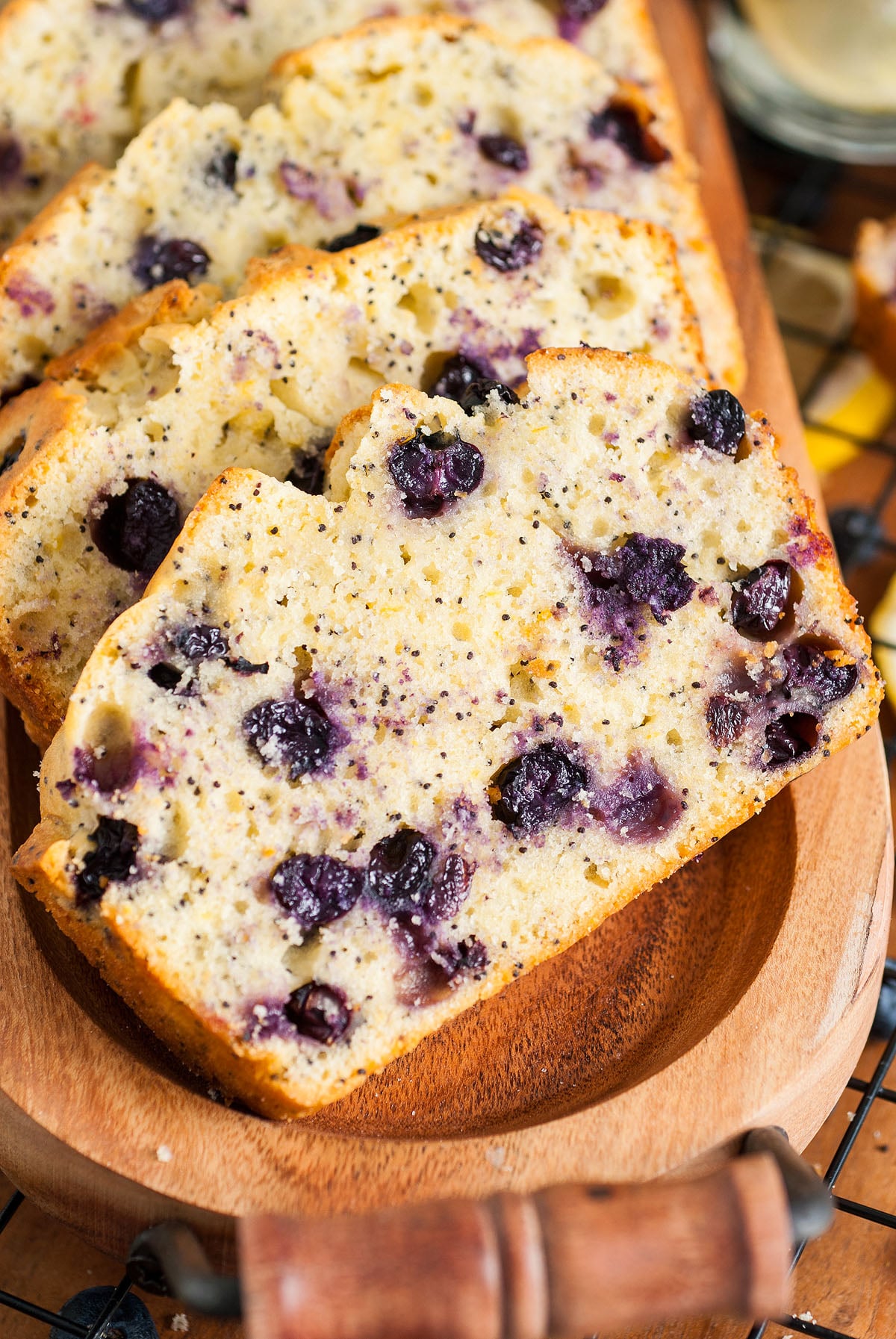 Sliced Lemon Blueberry Poppy Seed Loaf with visible blueberries and poppy seeds, served on a rustic wooden tray.