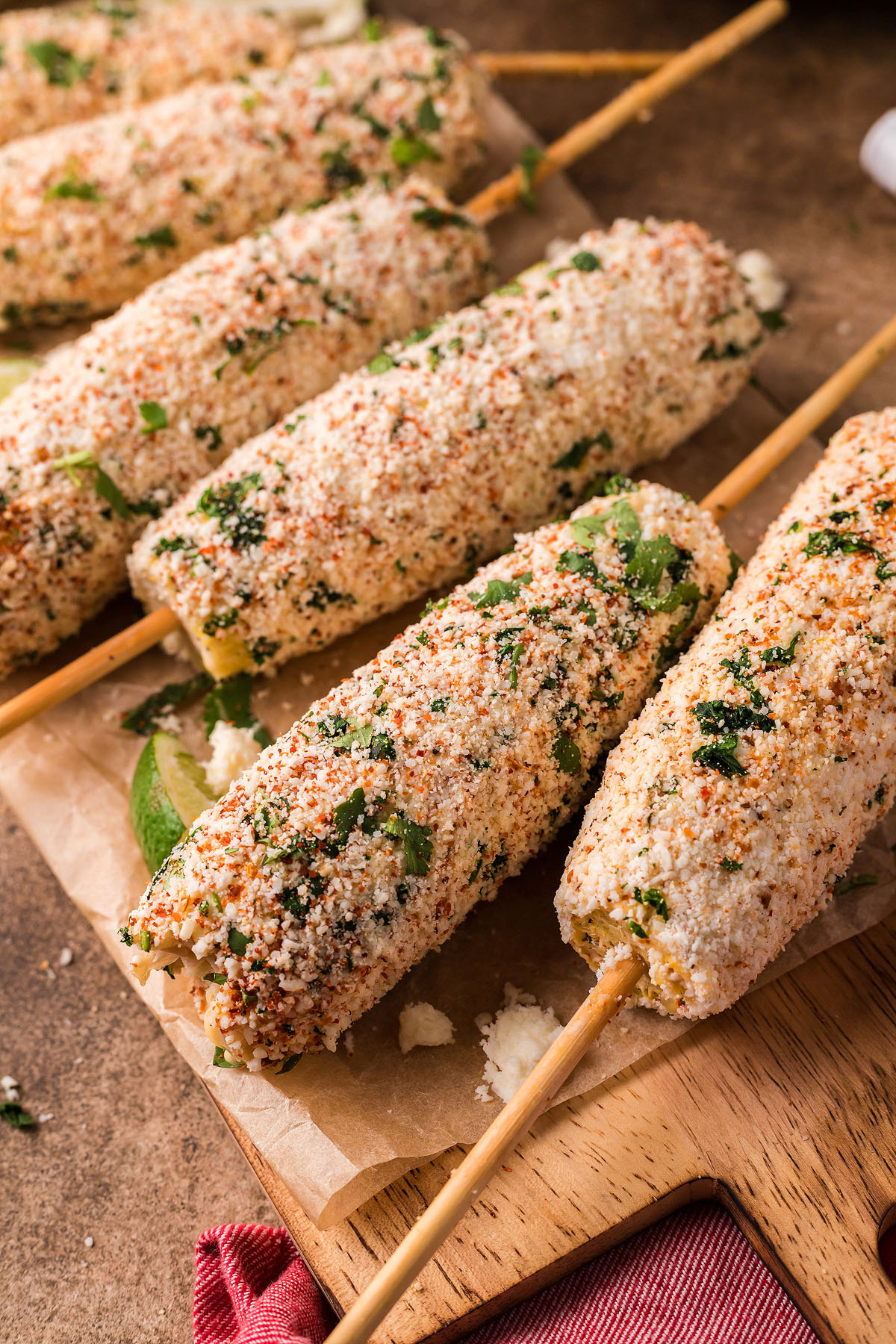 Smoked Elote – Mexican Street Corn on sticks, grilled to perfection and coated with cheese, herbs, and spices, served on parchment paper for an authentic flavor experience.