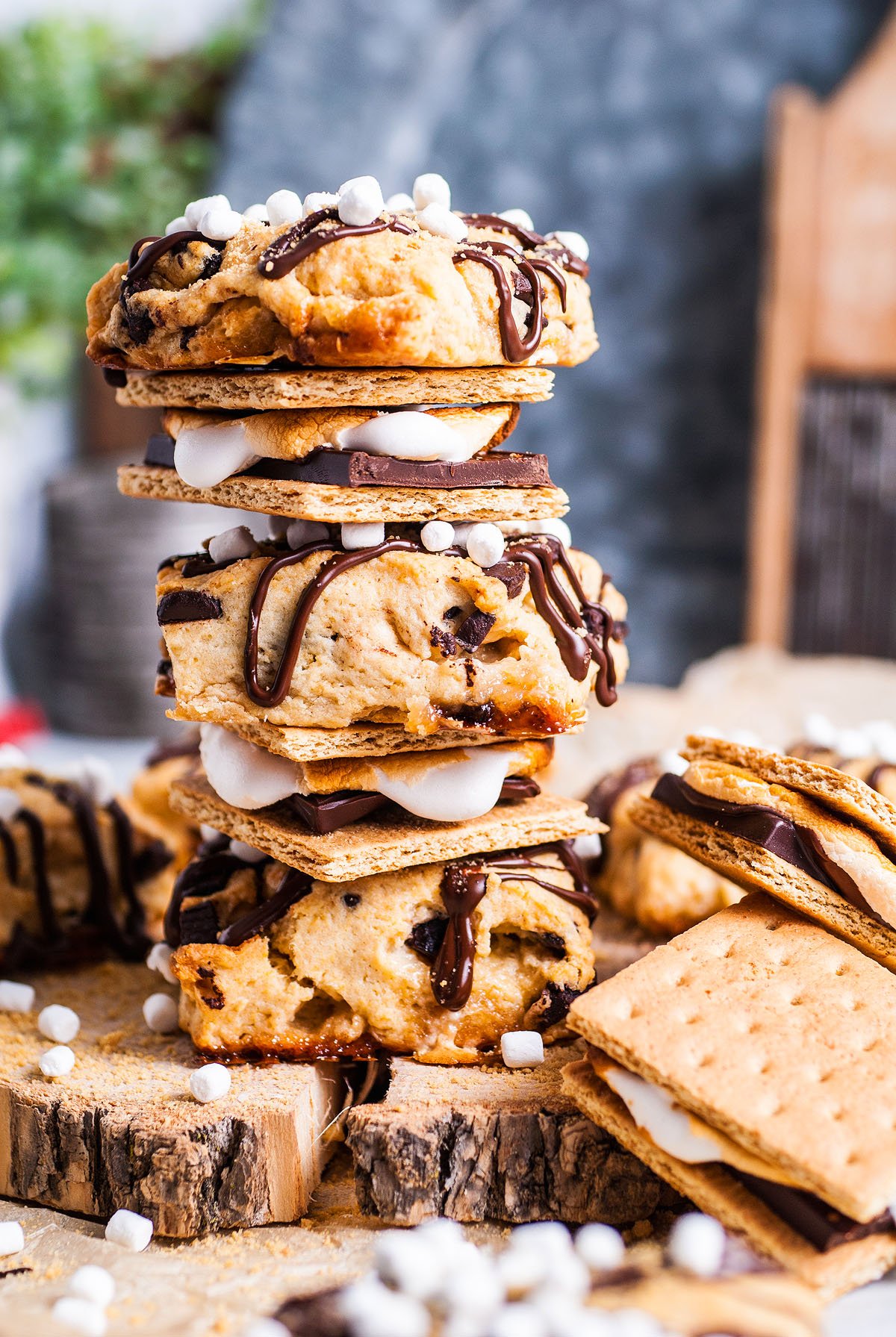 Three stacked s'mores with cookies, graham crackers, marshmallows, and chocolate drizzle on a rustic surface—perfect inspiration for your next S’more Scones or Chocolate Marshmallow Scones recipe.