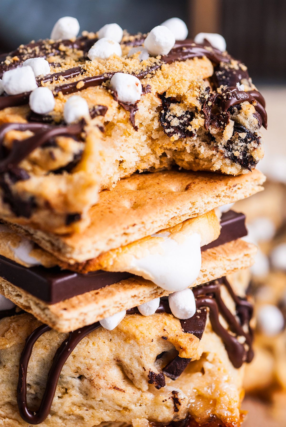 A stack of s’more scones with melted chocolate, marshmallows, and cookies, drizzled with chocolate sauce—an irresistible twist on a classic scones recipe.